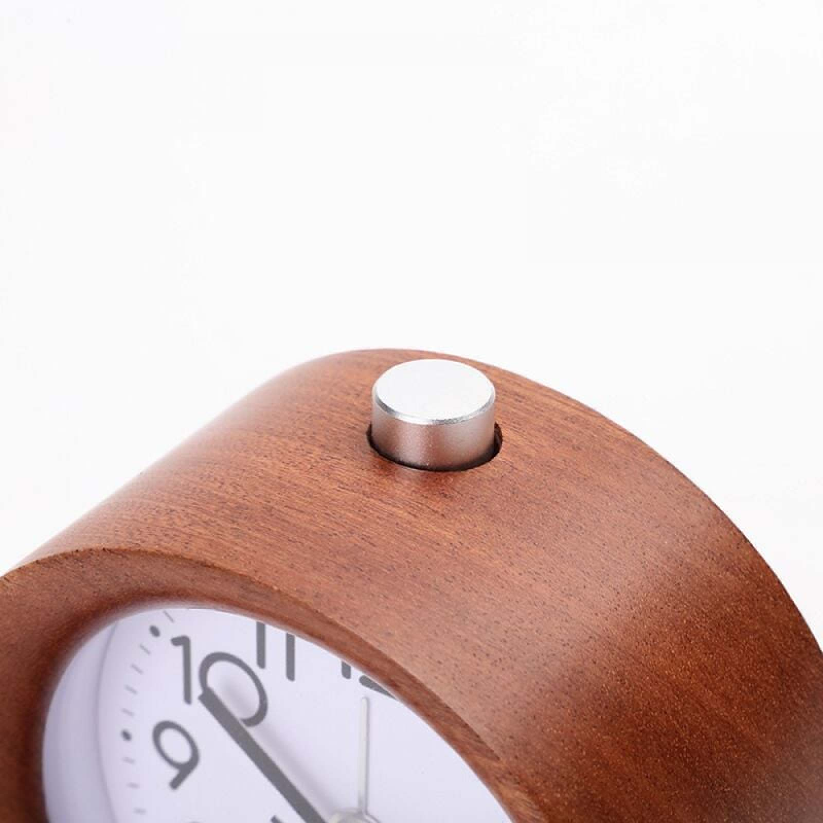 Ein brauner Holzwecker mit silbernem Knopf auf dem Zifferblatt.