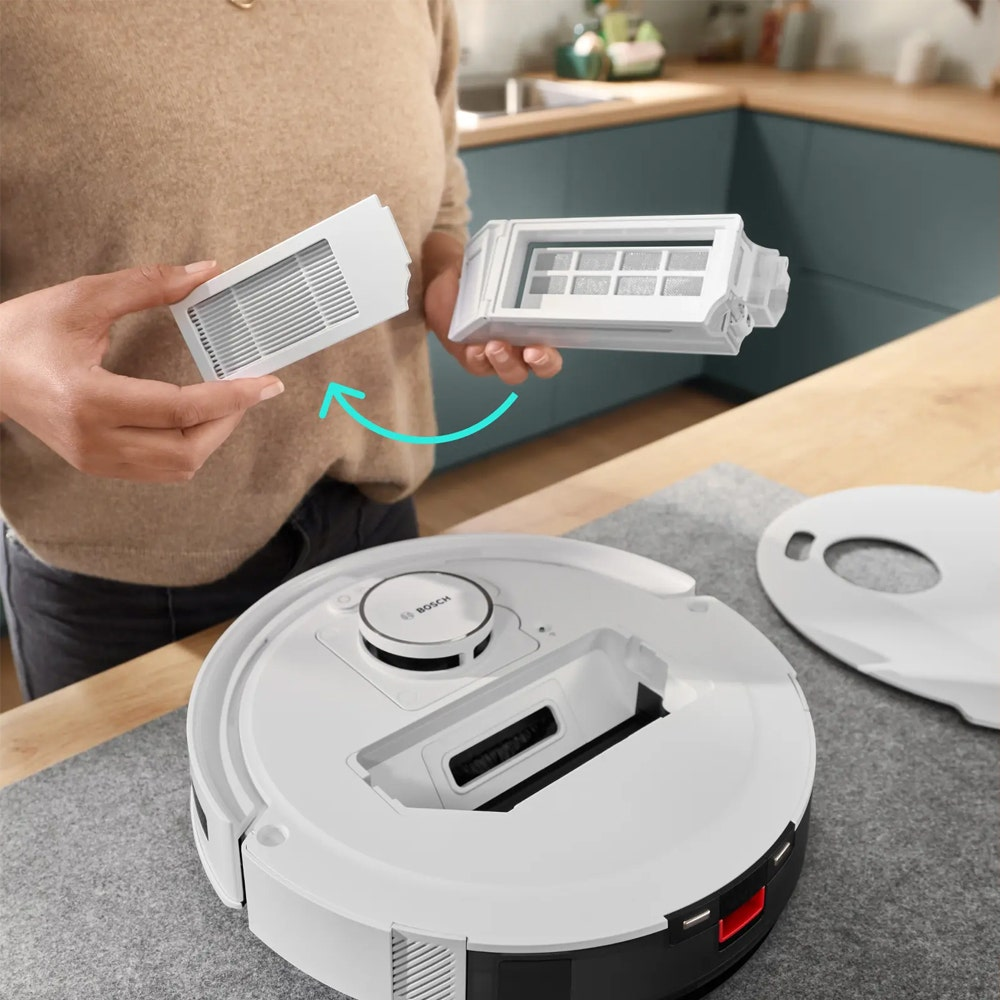 Eine Person hält einen weißen Staubfilter und setzt ihn in einen Saugroboter ein.