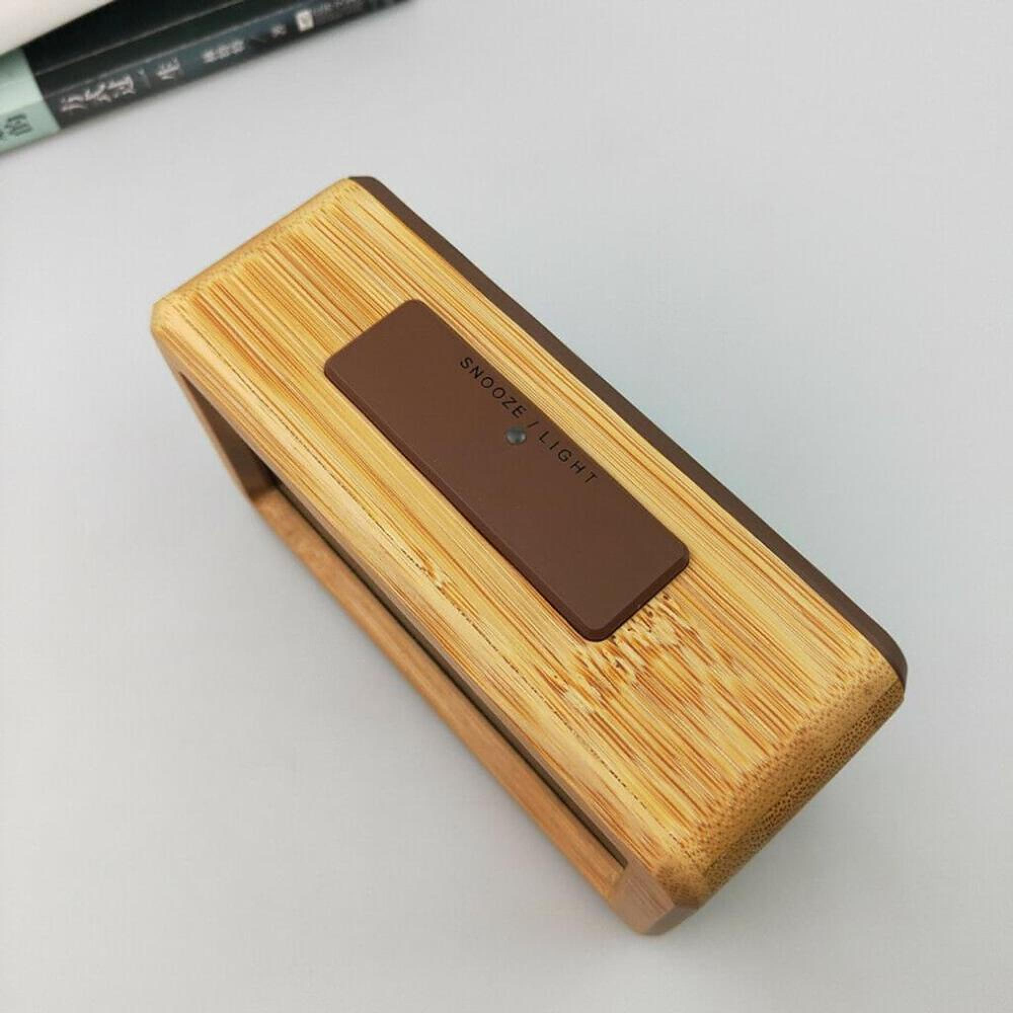 Ein digitaler Wecker aus Bambus mit brauner Snooze/Licht-Taste.