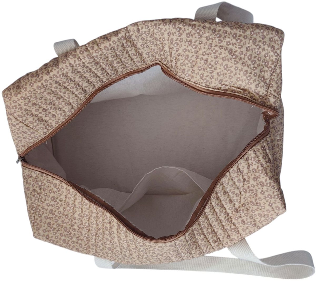 Eine beige gesteppte Tasche mit kleinem Blumenmuster und geöffnetem Reißverschluss.