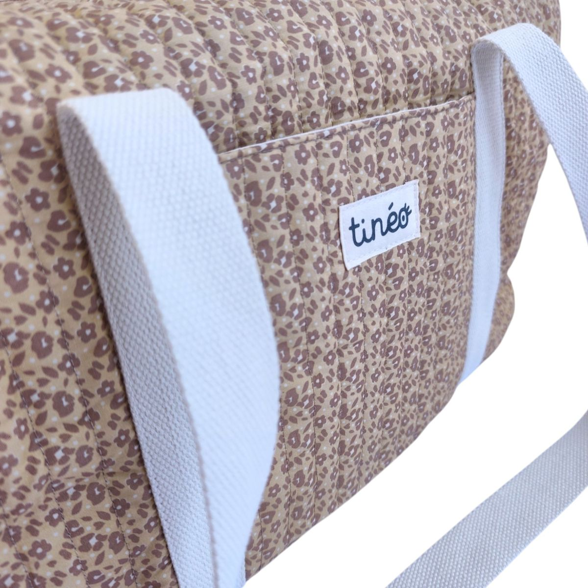 Braune Tasche mit Blumenmuster und weißen Trägern, mit dem Logo 
