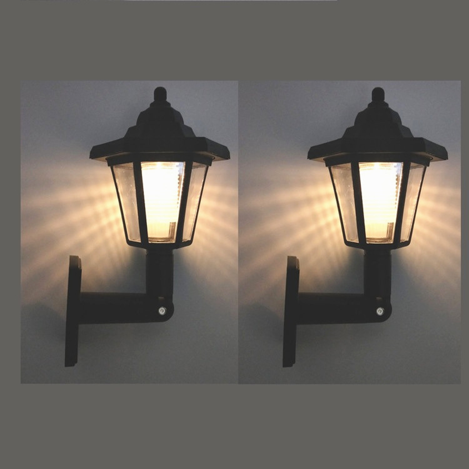 Zwei schwarze Wandleuchten mit Glasfenstern leuchten auf einem grauen Hintergrund.