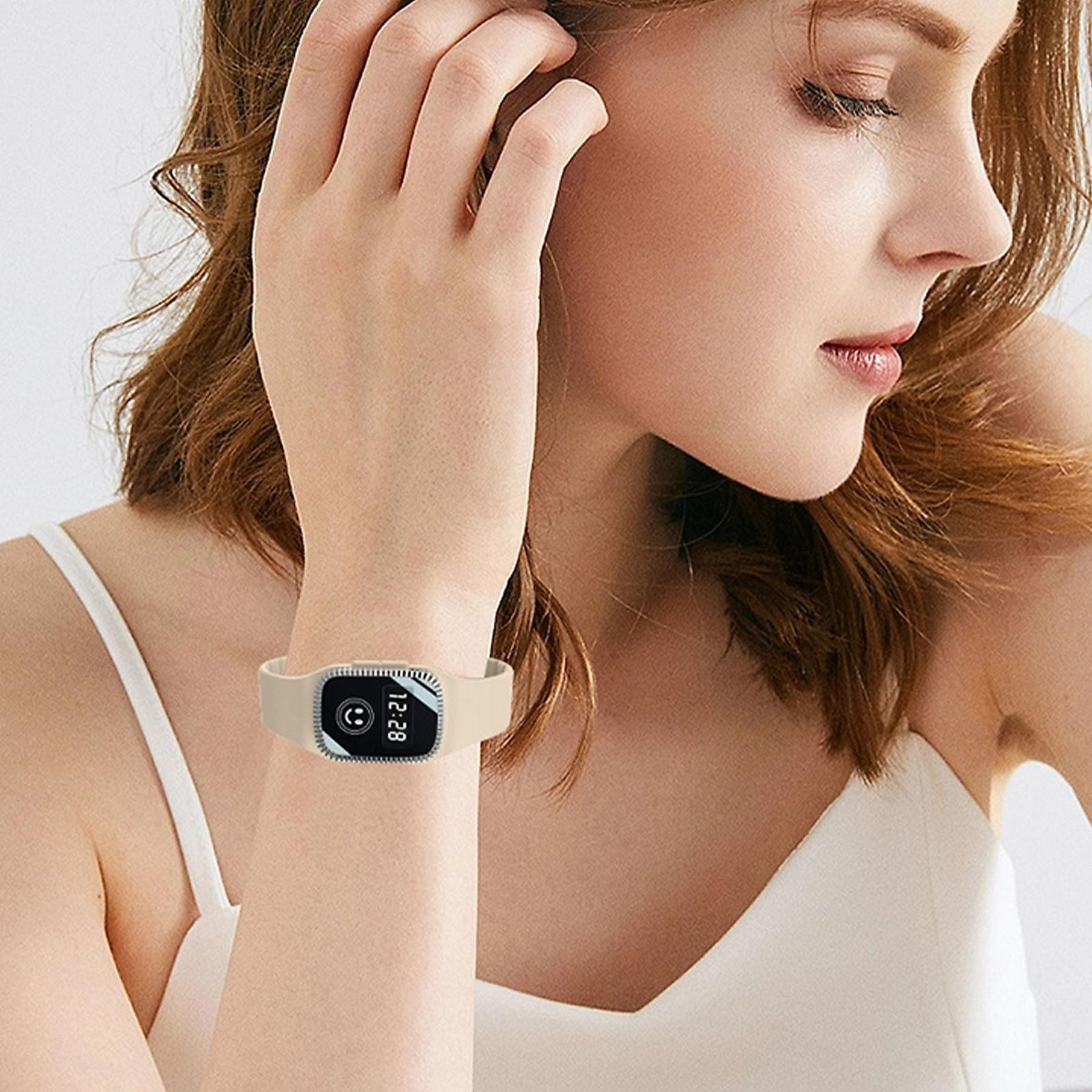 Eine Frau mit braunem Haar trägt ein hellbeiges Armband mit einem digitalen Display.