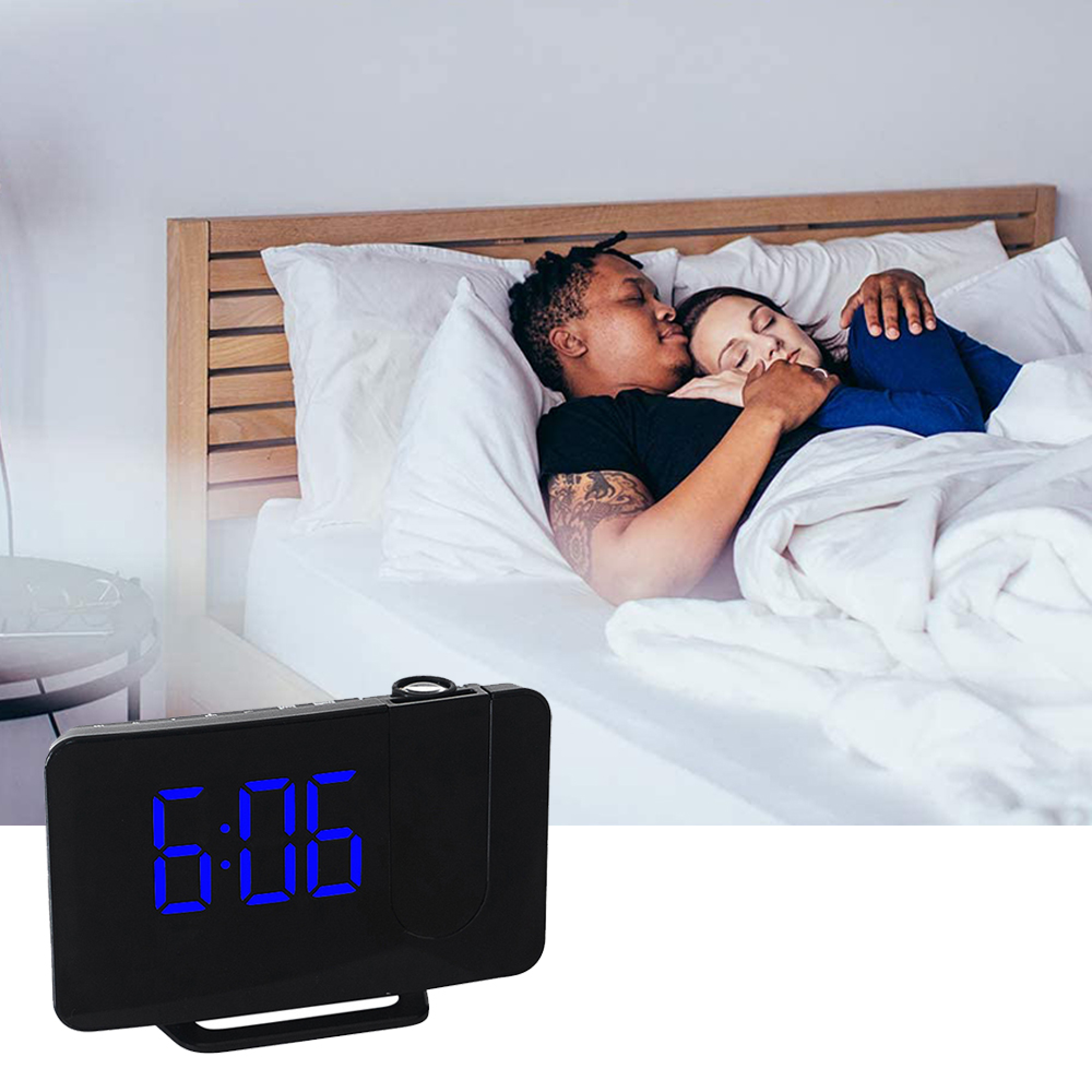Ein Mann küsst eine schlafende Frau im Bett, ein Projektionswecker zeigt 6:06.