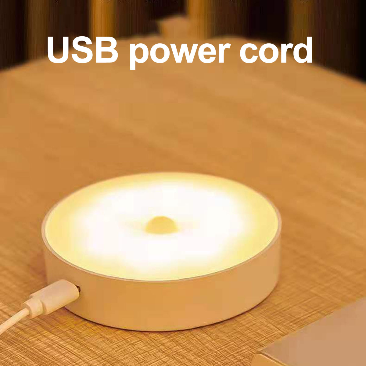 Ein weißes USB-Netzkabel ist an ein rundes, beleuchtetes Gerät auf einer Holzoberfläche angeschlossen.