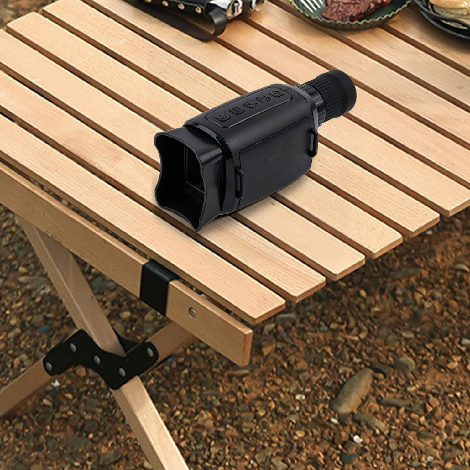 Ein schwarzes Nachtsichtgerät liegt auf einem Holztisch. Der Hintergrund ist unscharf.