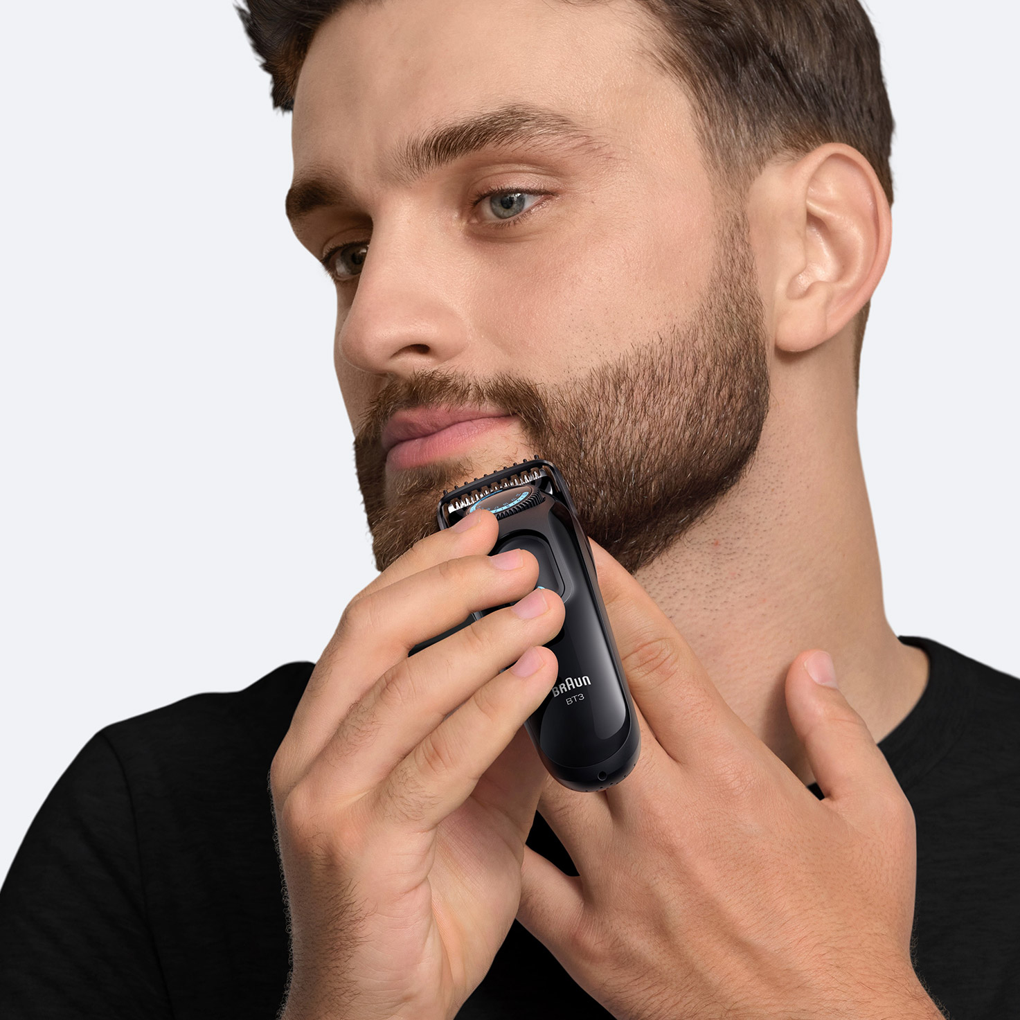 Mann mit Barttrimmer, der sein Gesicht trimmt. Schwarzer
Schal. Heller Hintergrund.