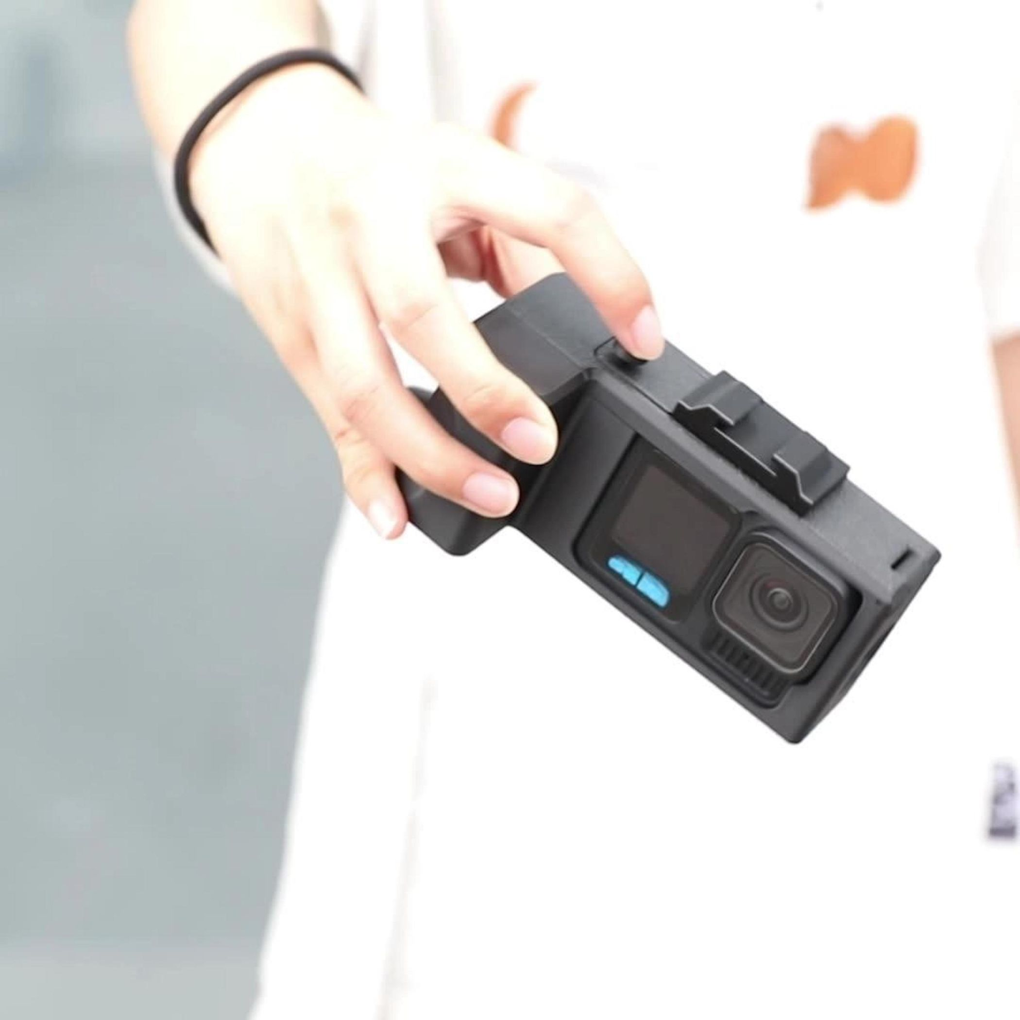 Eine Hand hält eine schwarze Kamera in einer schwarzen Hülle.