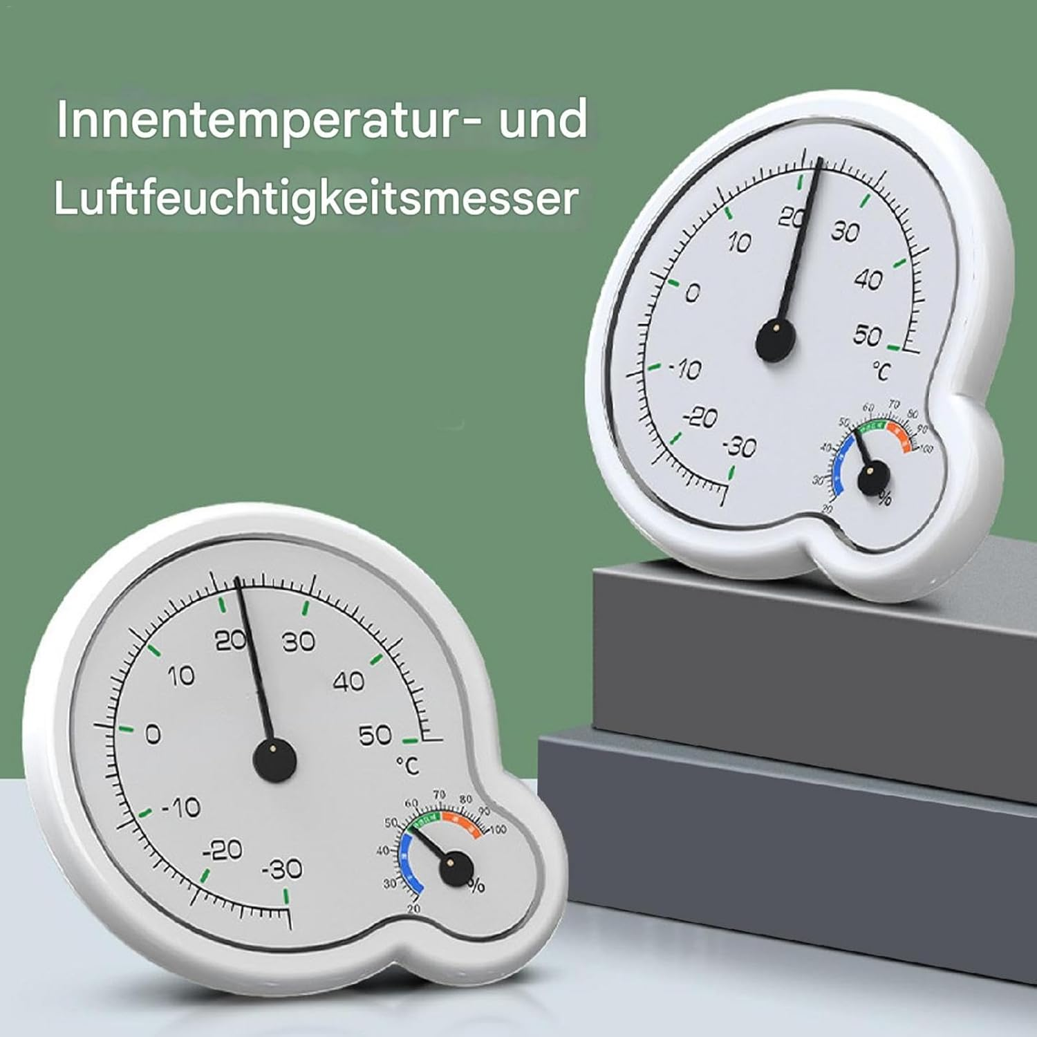 Zwei weiße Thermometer und Hygrometer mit schwarzen Zeigern auf grünem Hintergrund.