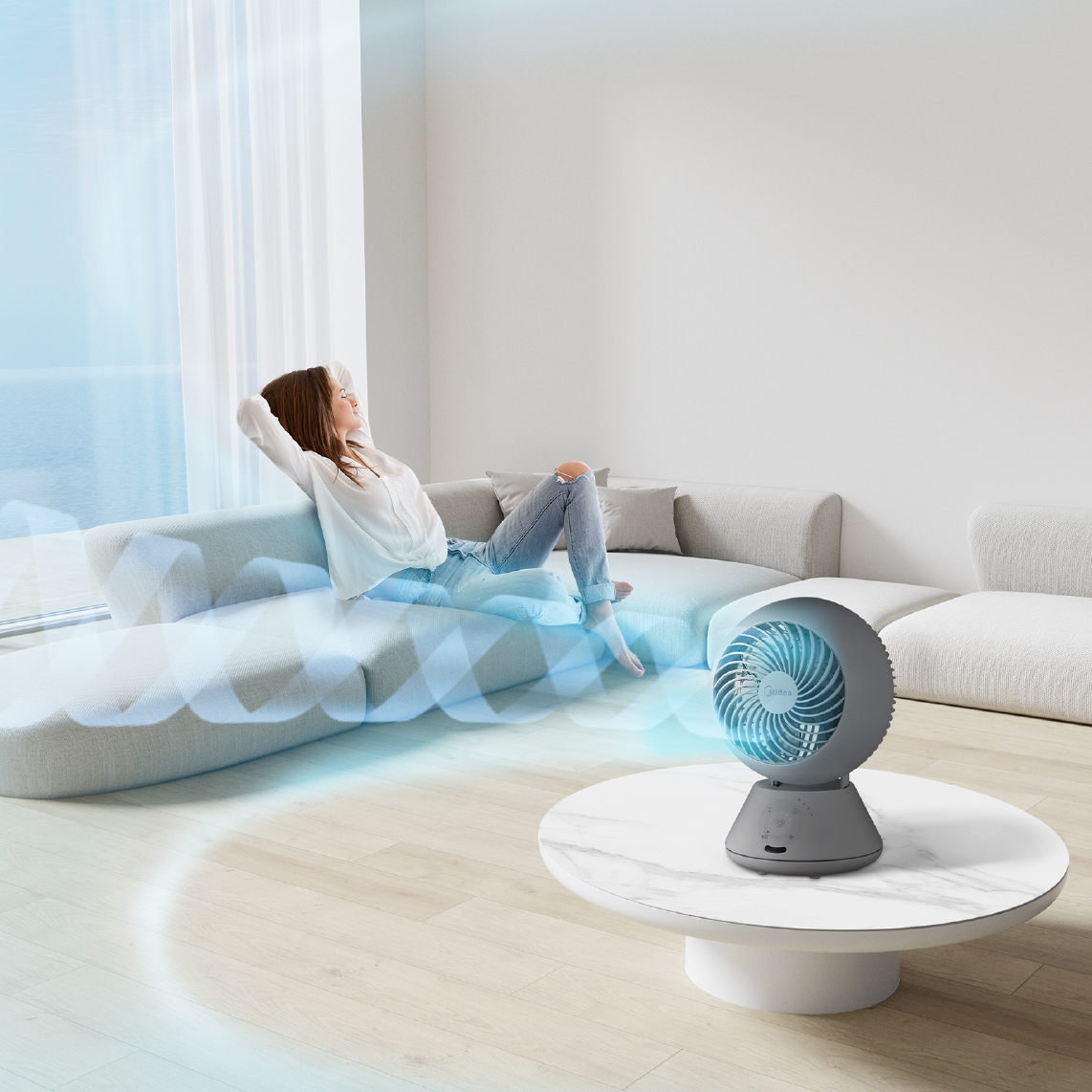 Eine Frau entspannt sich auf einem Sofa, während ein Ventilator kühle Luft in den Raum bläst.