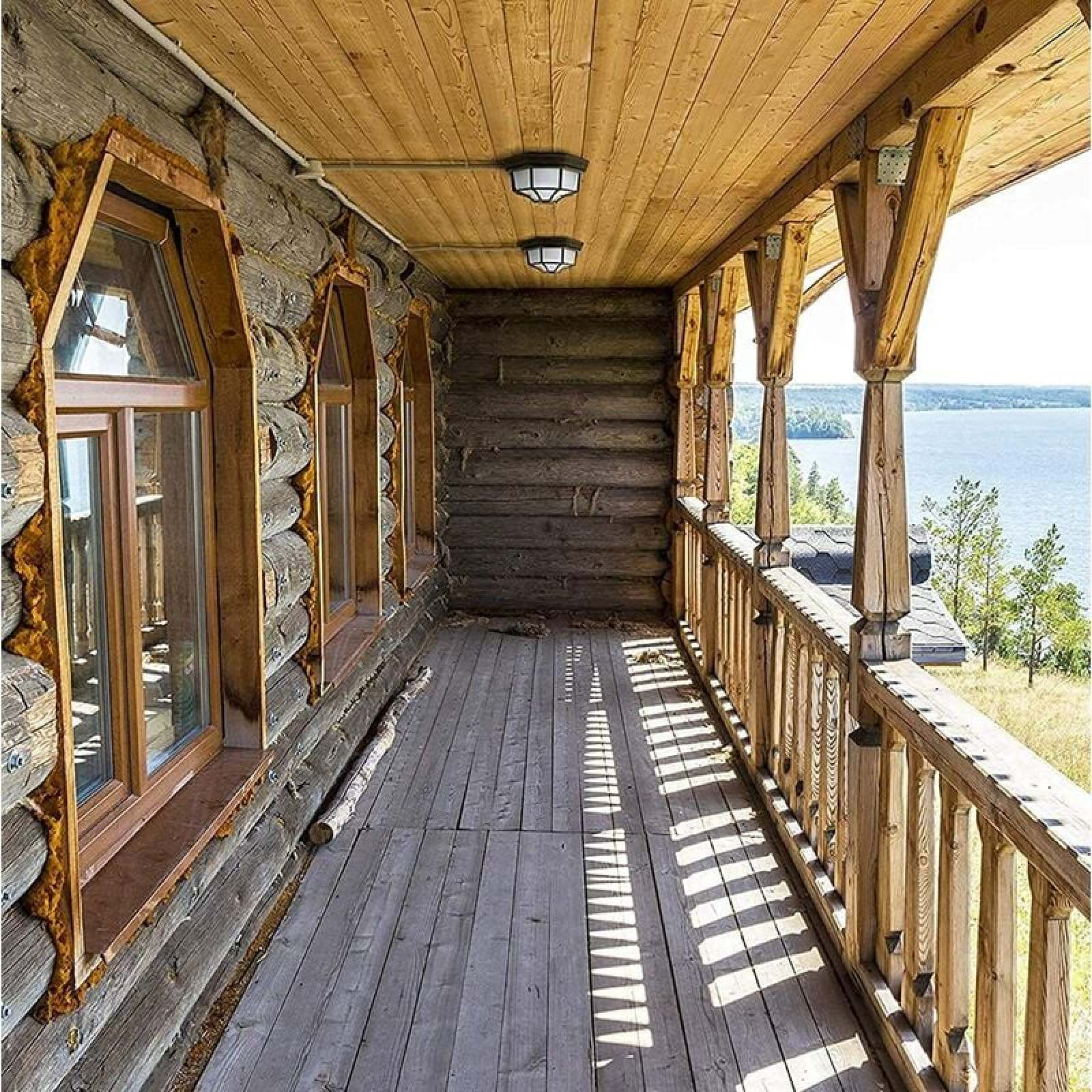Holzbalkon mit Blick auf den See, mit Holzstämmen und Fenstern.