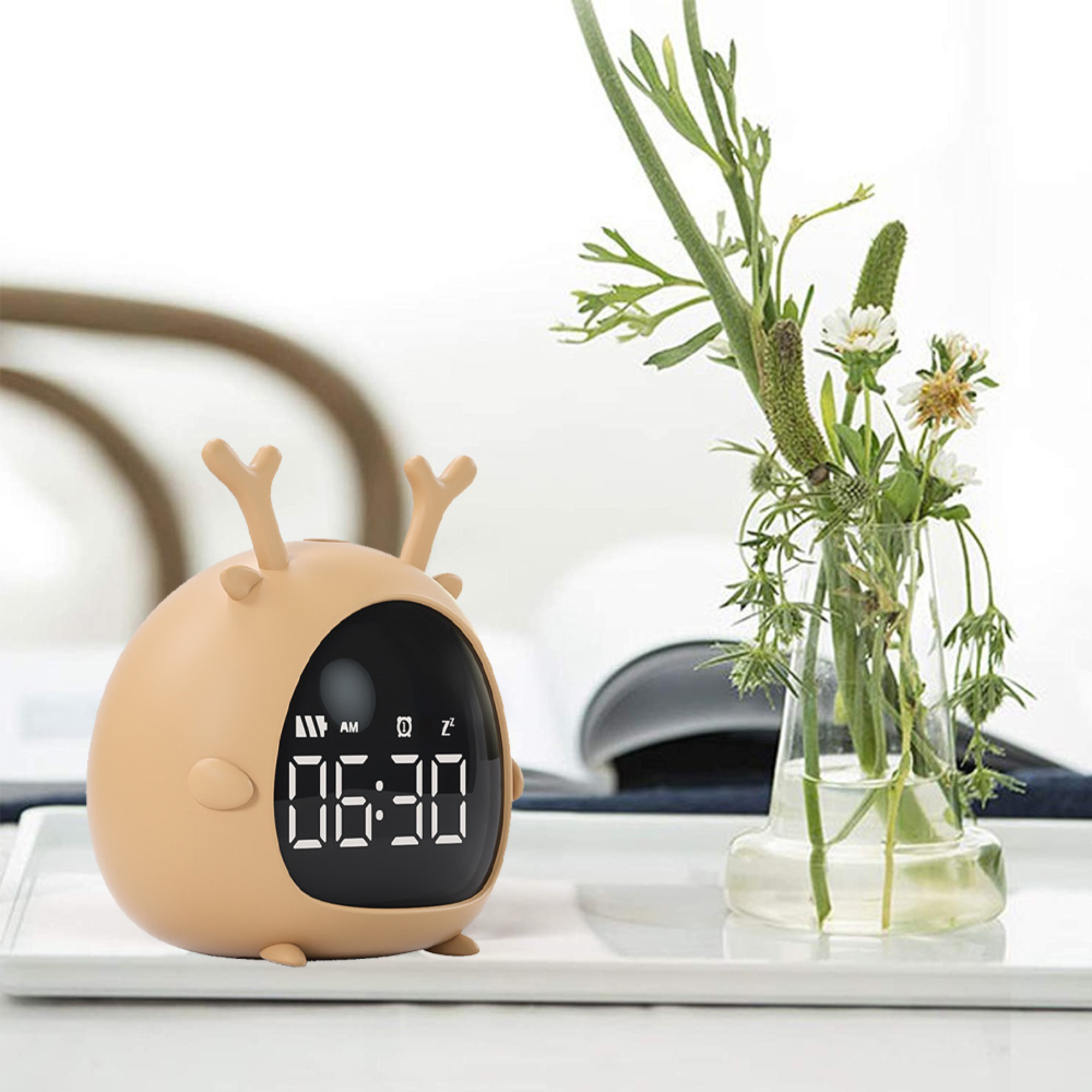 Ein beiger Wecker in Rehform zeigt 06:30 an. Daneben steht eine Vase mit Pflanzen.