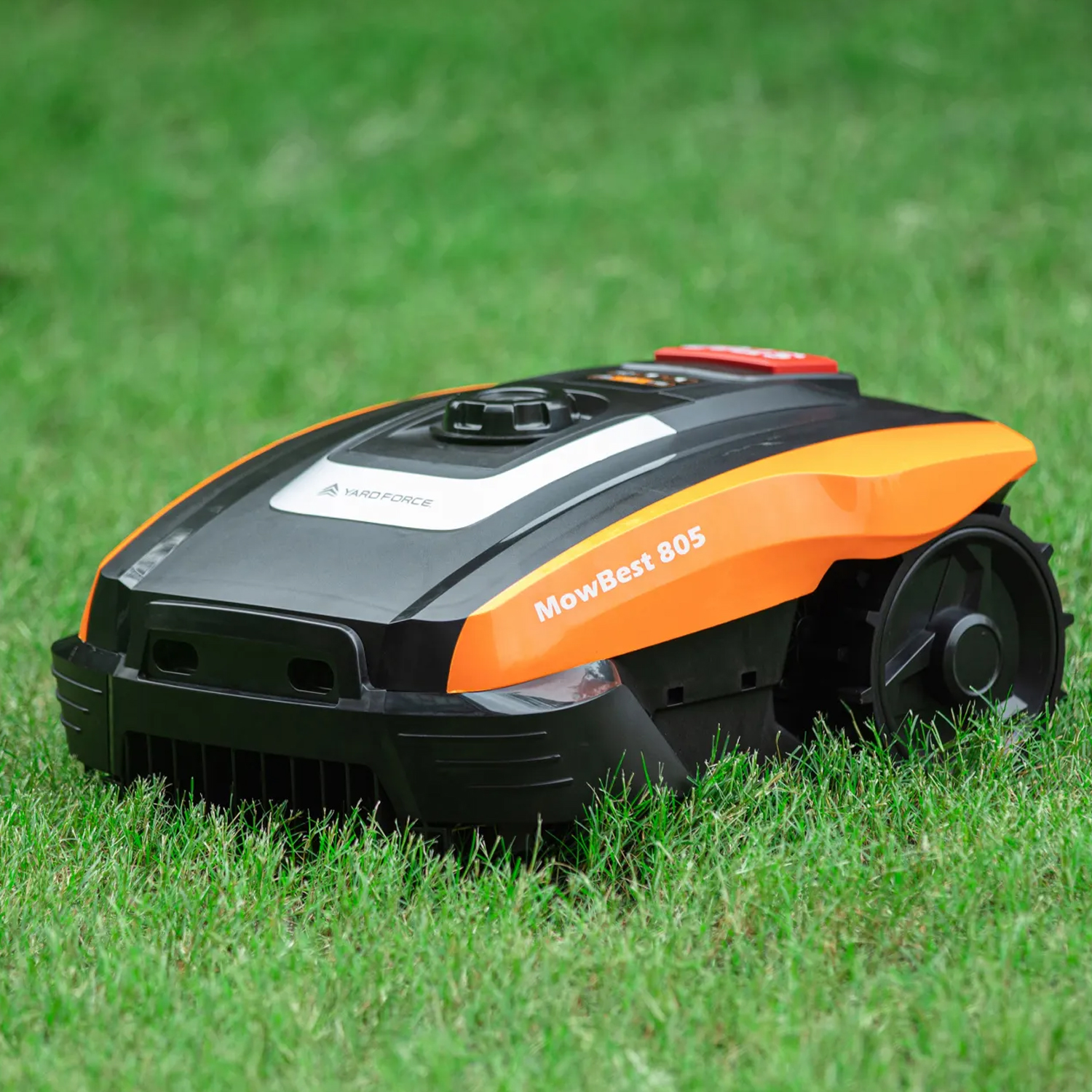 Ein schwarzer und oranger Roboter-Rasenmäher steht auf einem grünen Rasen.
