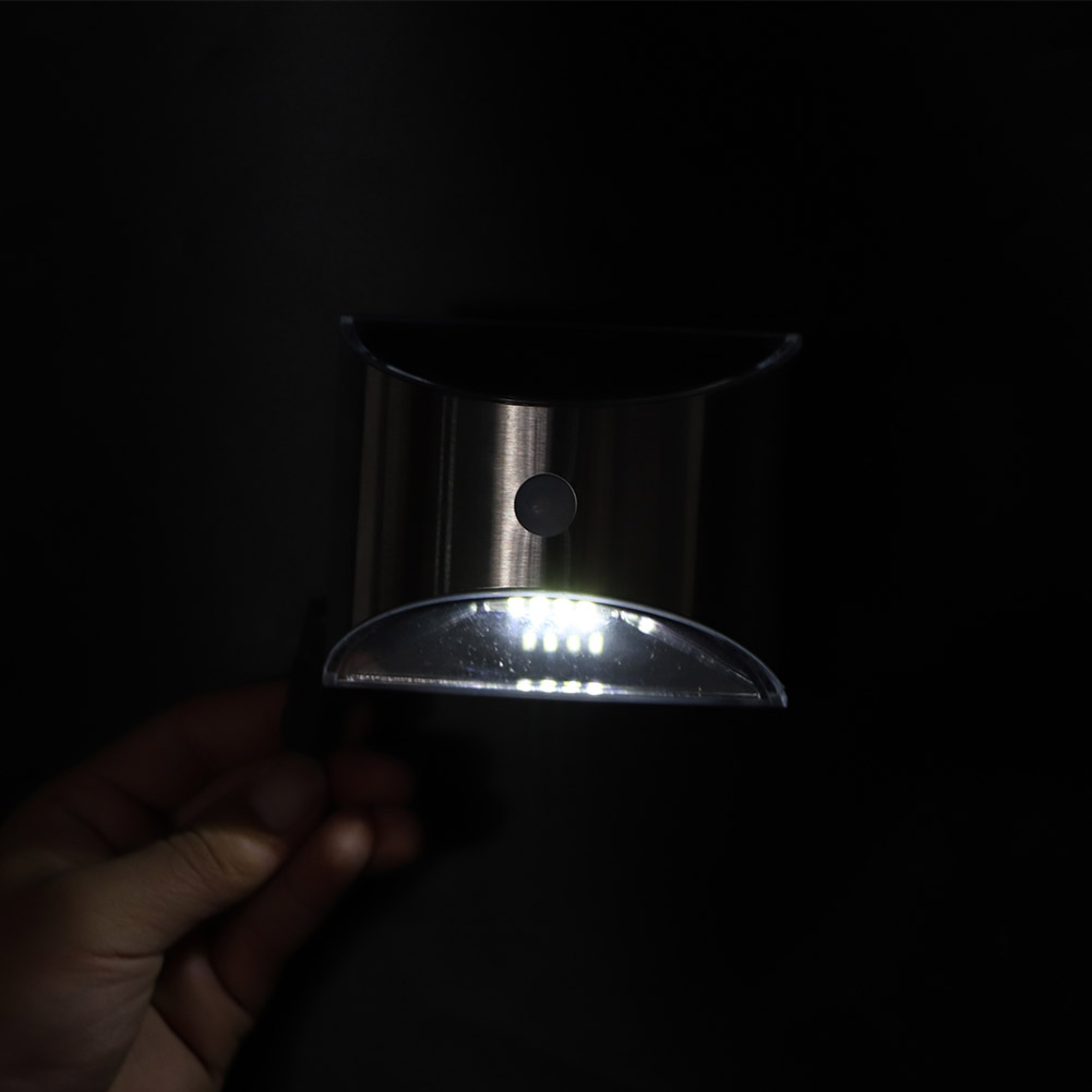 Ein silbernes Solarlicht mit eingeschalteten LEDs, das von einer Hand gehalten wird.