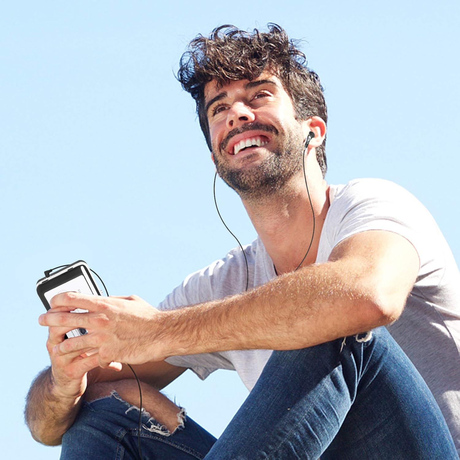 Ein Mann mit Kopfhörern und Smartphone sitzt im Freien.