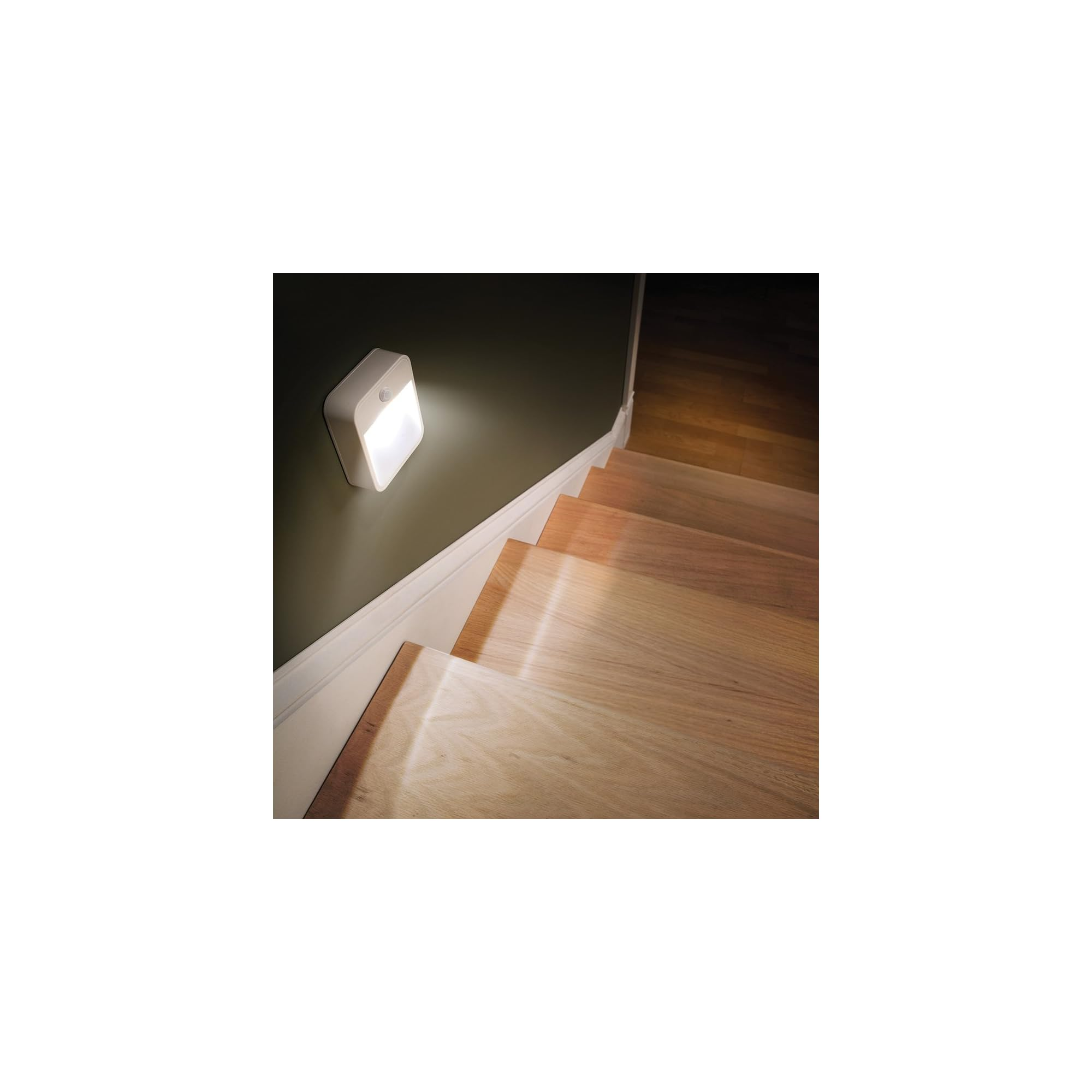 Ein weißes Nachtlicht leuchtet auf einer dunklen Wand über einer Holztreppe.