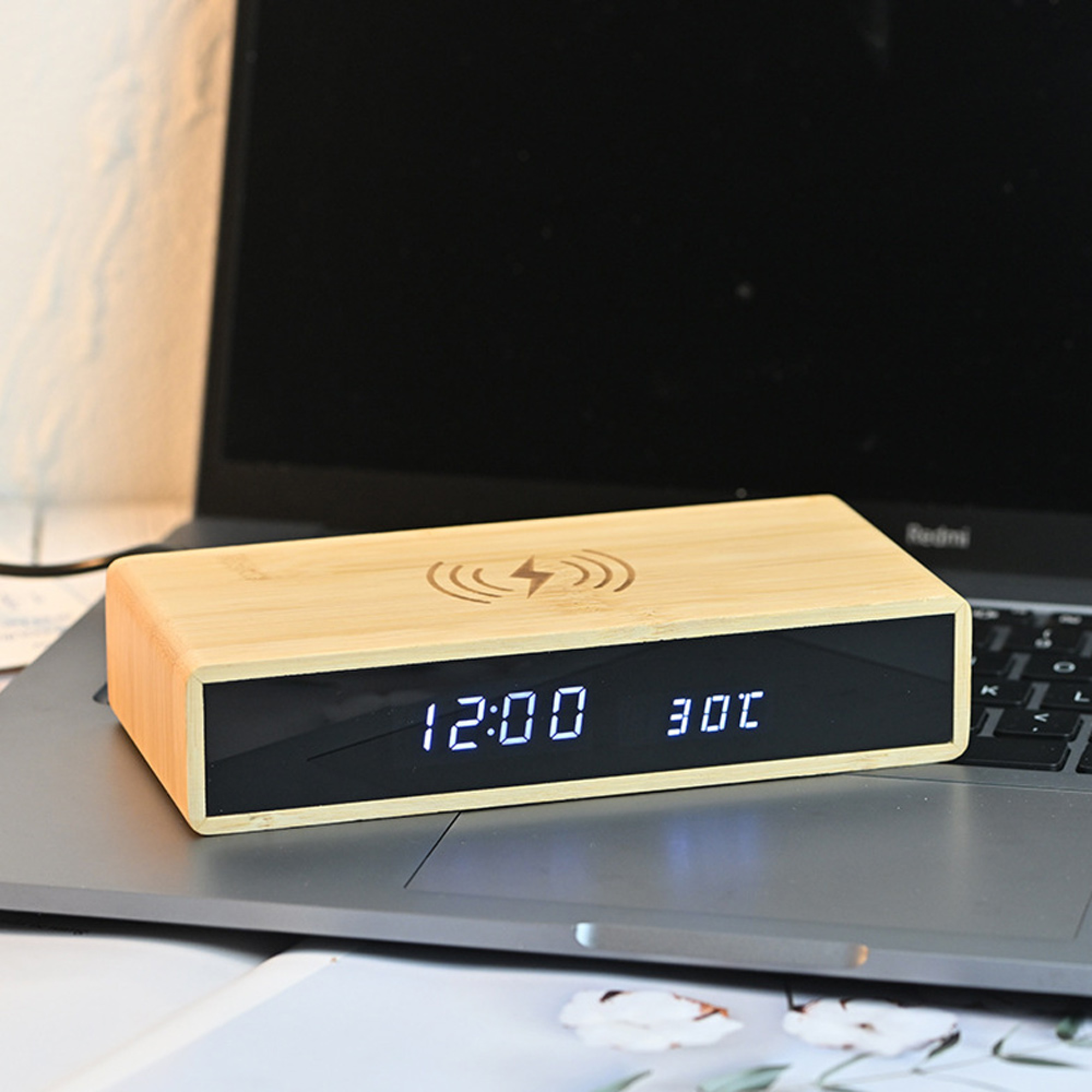 Ein Holz-Digitalwecker mit Ladefunktion auf einem Laptop.