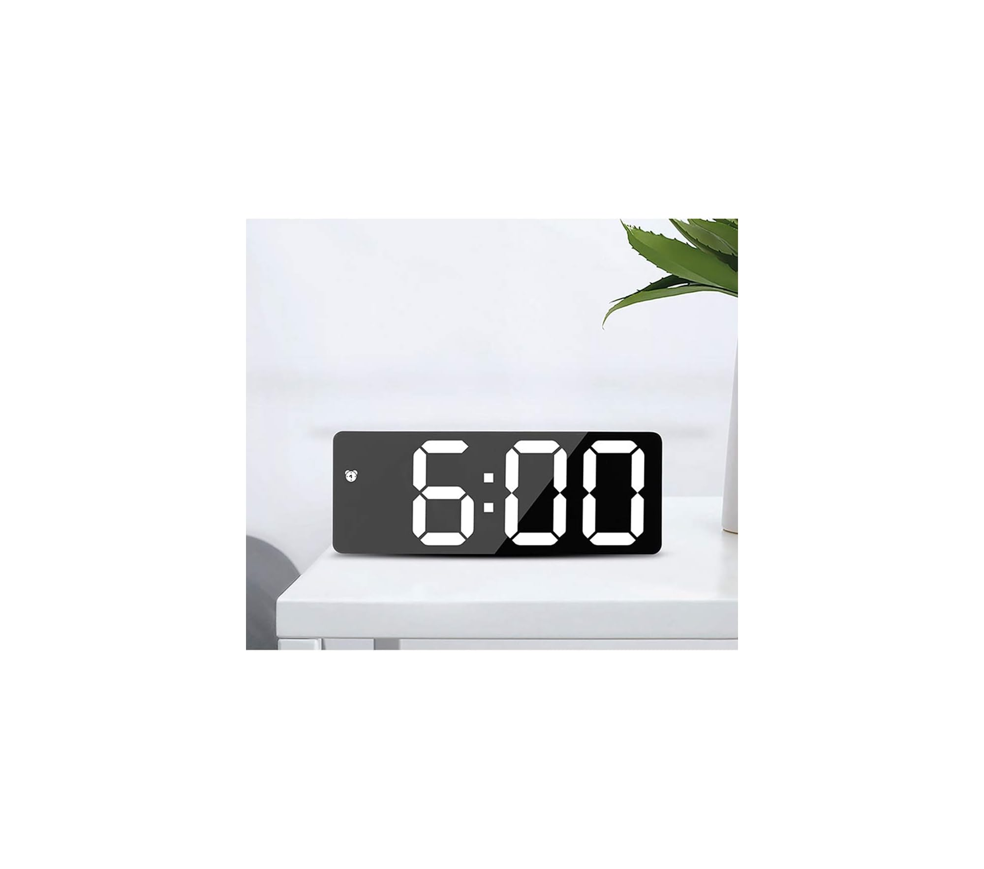 Ein schwarzer Digitalwecker zeigt 6:00 auf einem weißen Tisch.