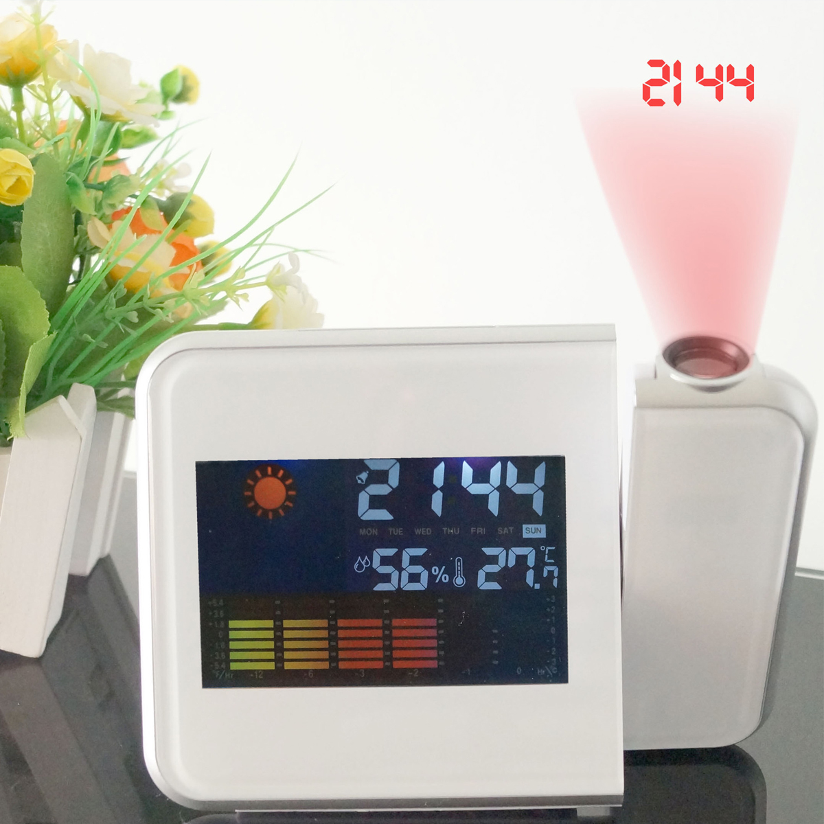 Ein digitaler Projektionswecker zeigt 21:44 an, mit Wetterdaten und Blumen im Hintergrund.