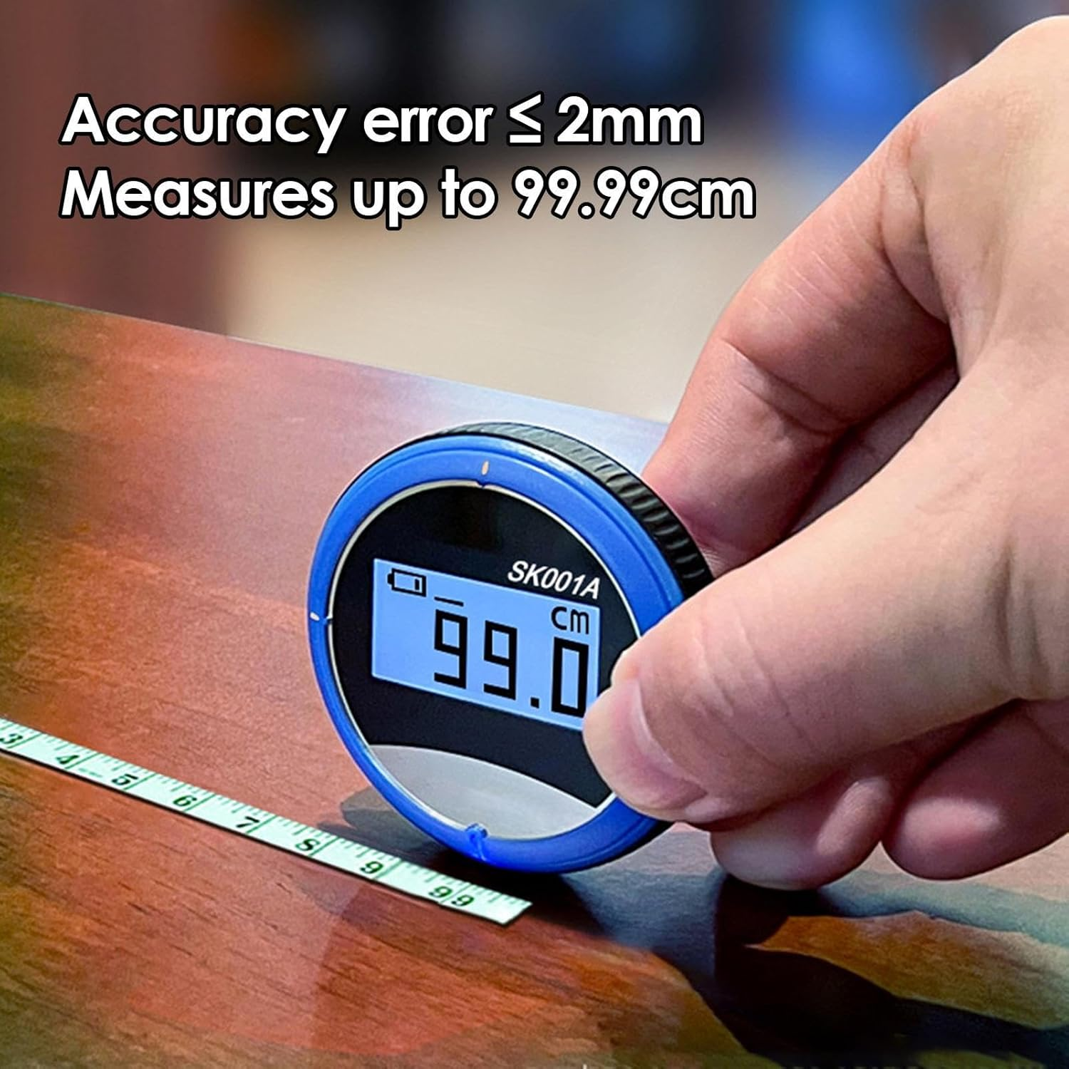 Ein digitales Messgerät zeigt 99,0 cm an. Ein Maßband liegt daneben.
