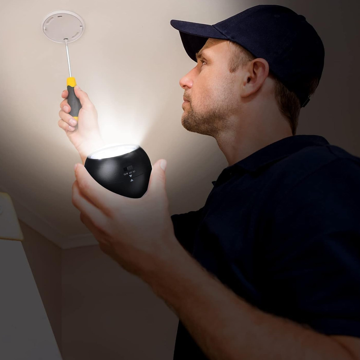 Mann mit Schraubendreher und Licht arbeitet an Deckenrauchmelder.