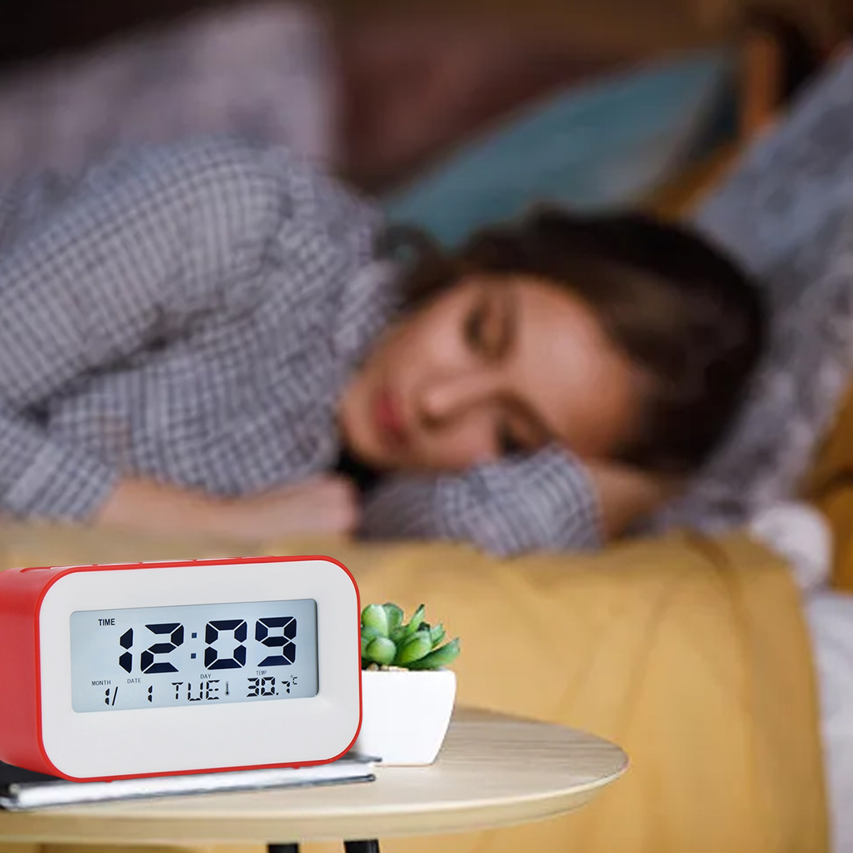 Eine Person schläft im Bett, ein digitaler Wecker zeigt 12:09 an.