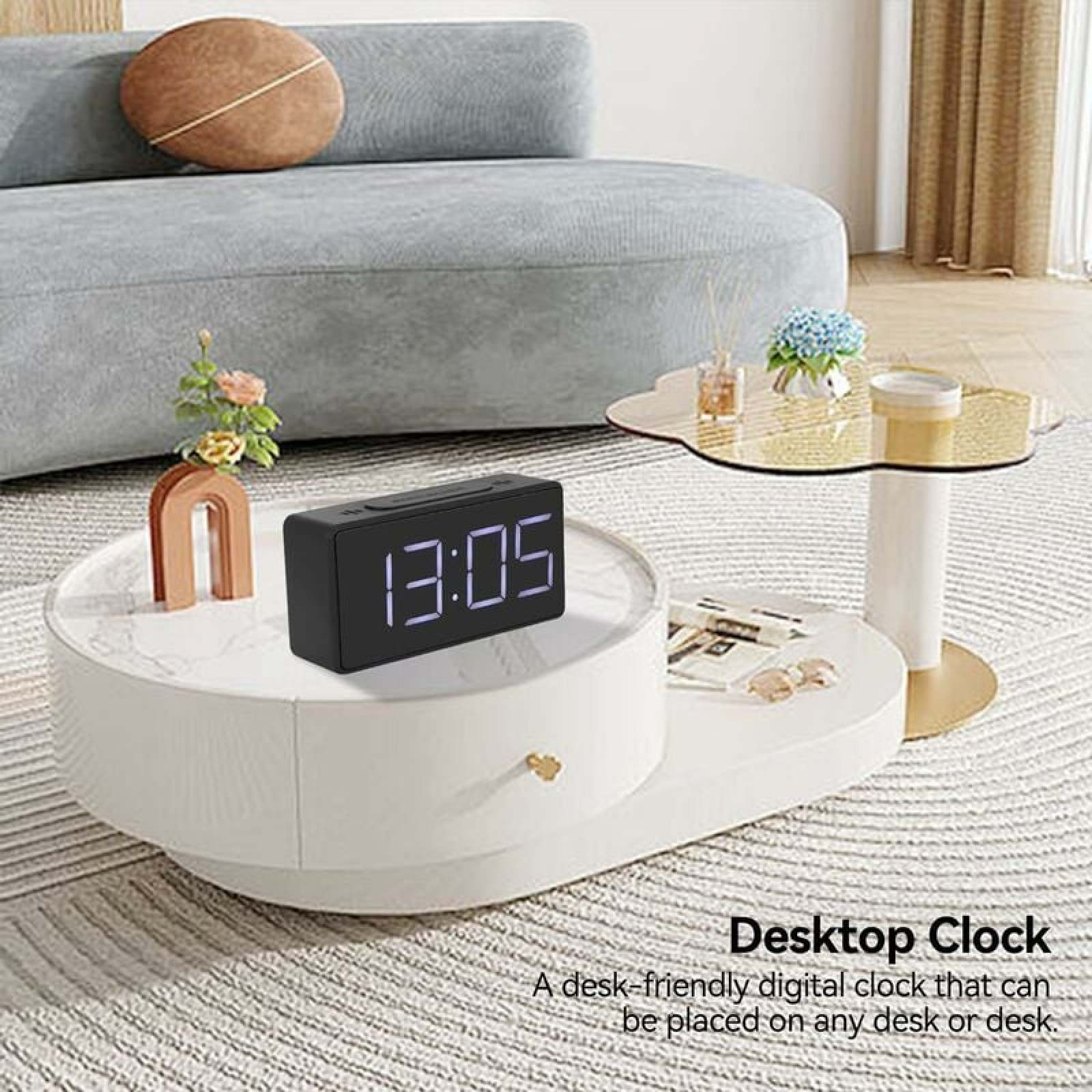 Schwarze Digitaluhr zeigt 13:05 auf einem weißen Couchtisch neben einem Sofa.