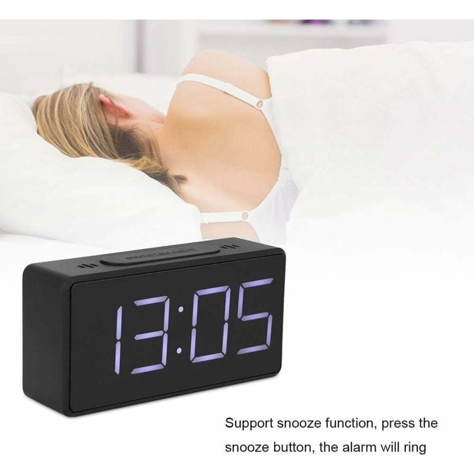 Eine Person schläft, ein digitaler Wecker zeigt 13:05.