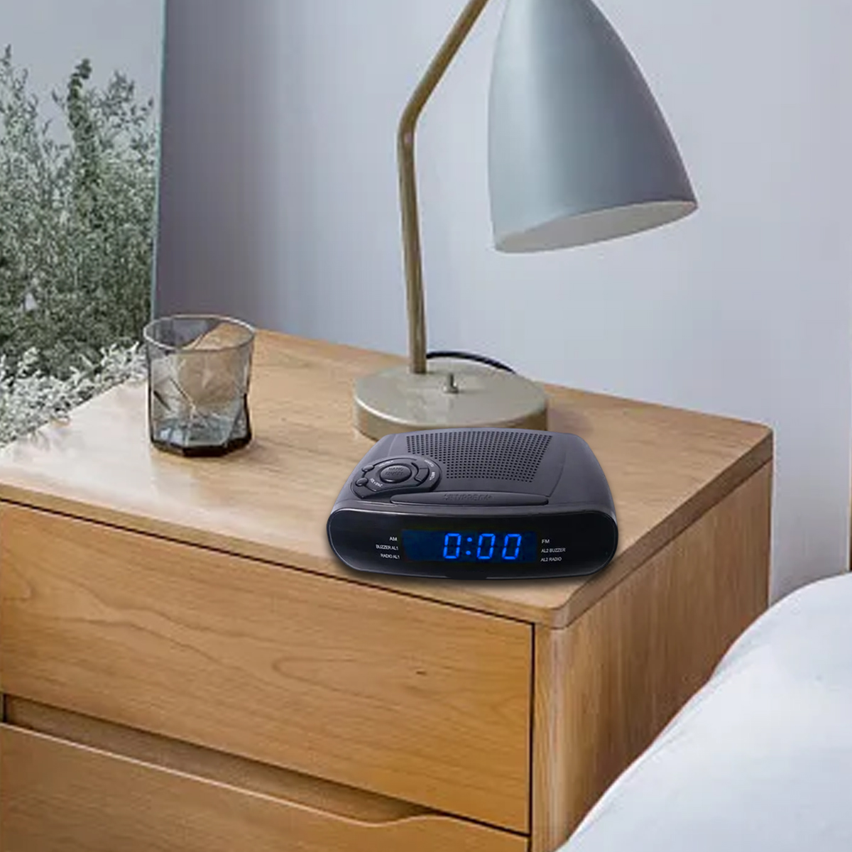 Ein schwarzer Radiowecker mit blauem Digitaldisplay steht auf einem Nachttisch aus Holz.