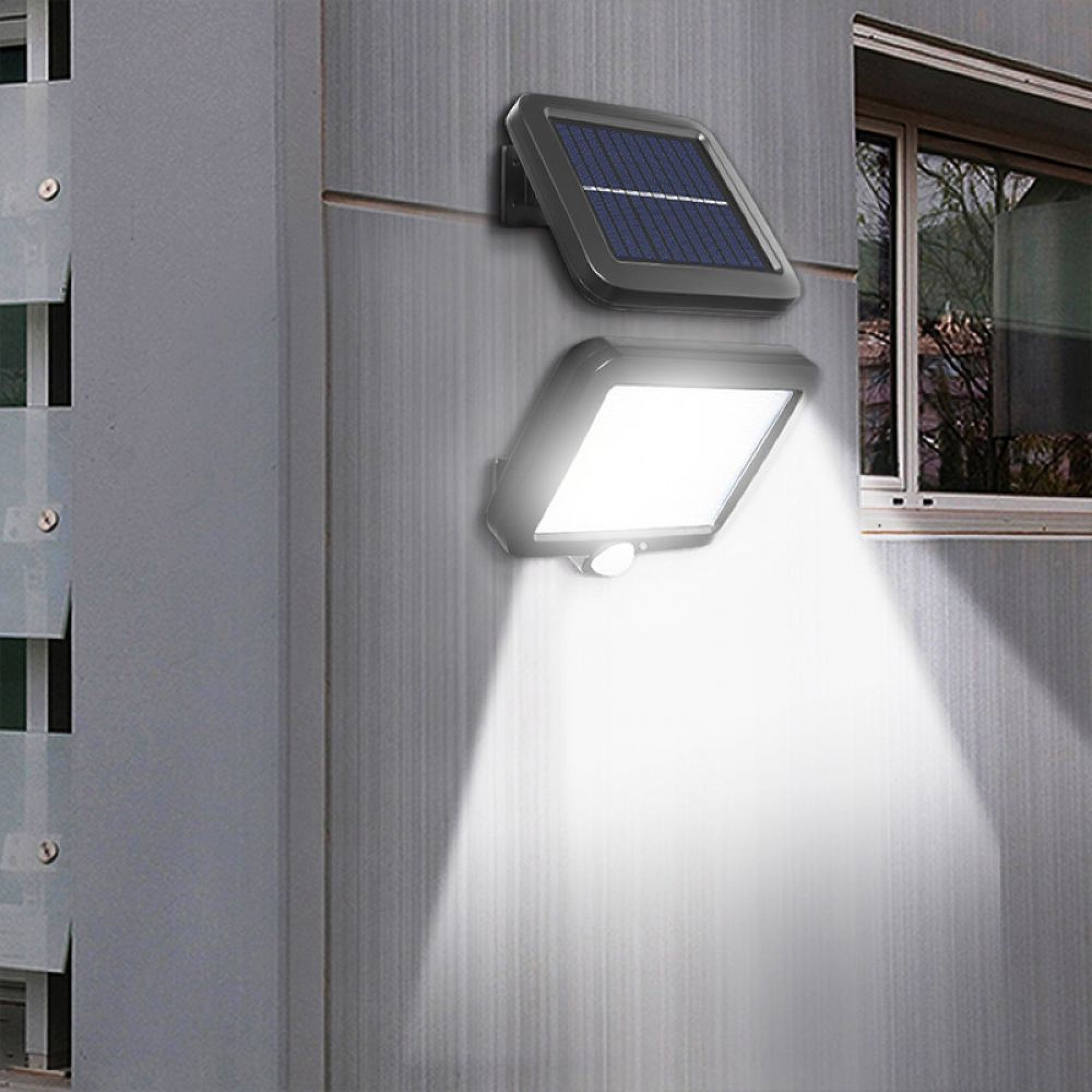 Ein Solar-Außenstrahler mit Bewegungsmelder an einer grauen Wand, daneben ein Fenster.