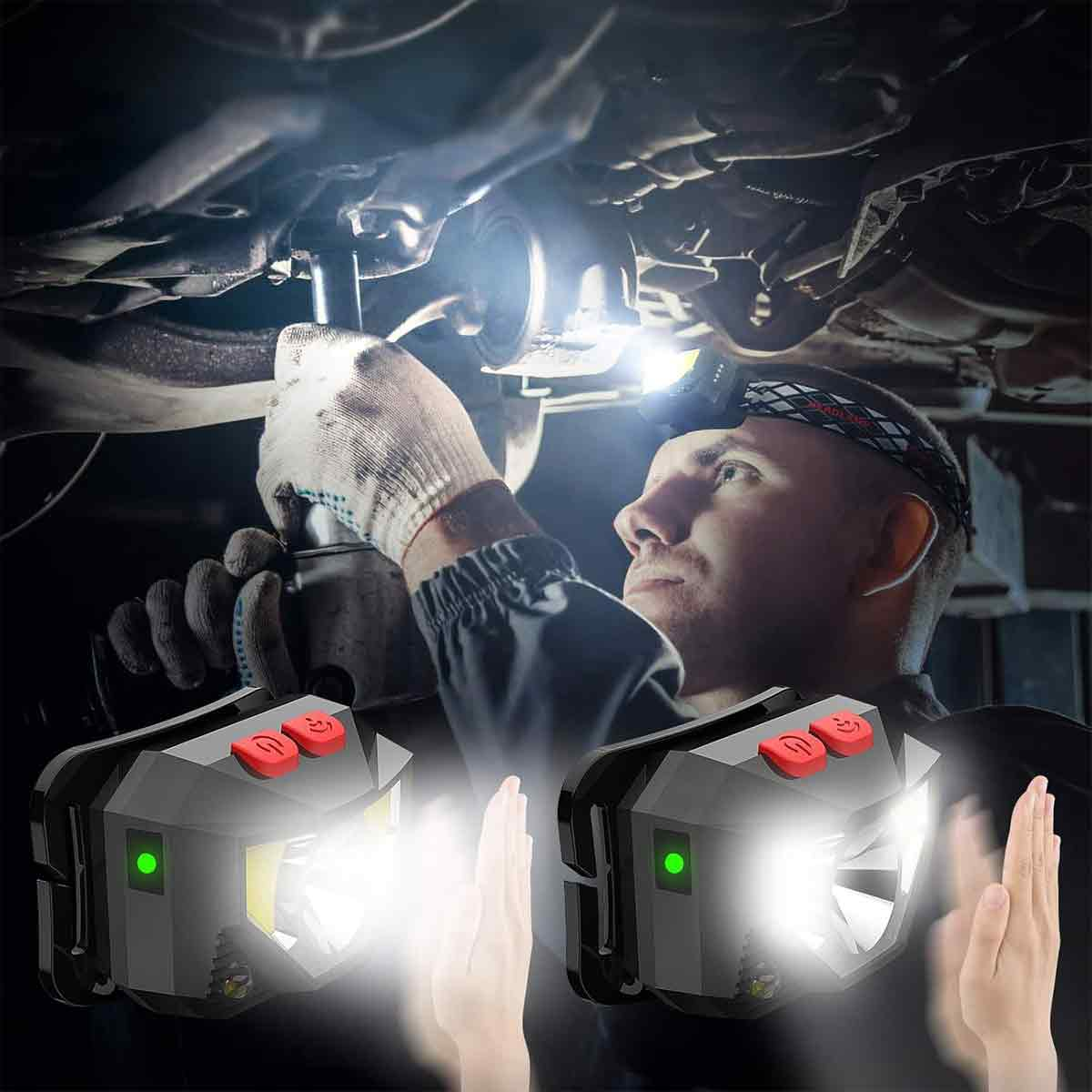 Mechaniker mit Stirnlampe arbeitet am Auto-Unterboden, zwei Stirnlampen im Vordergrund.