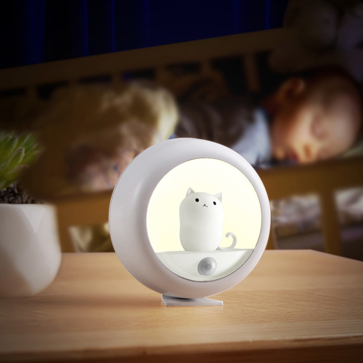 Niedliche Katze Lampe leuchtet neben schlafendem Baby im Kinderbett.