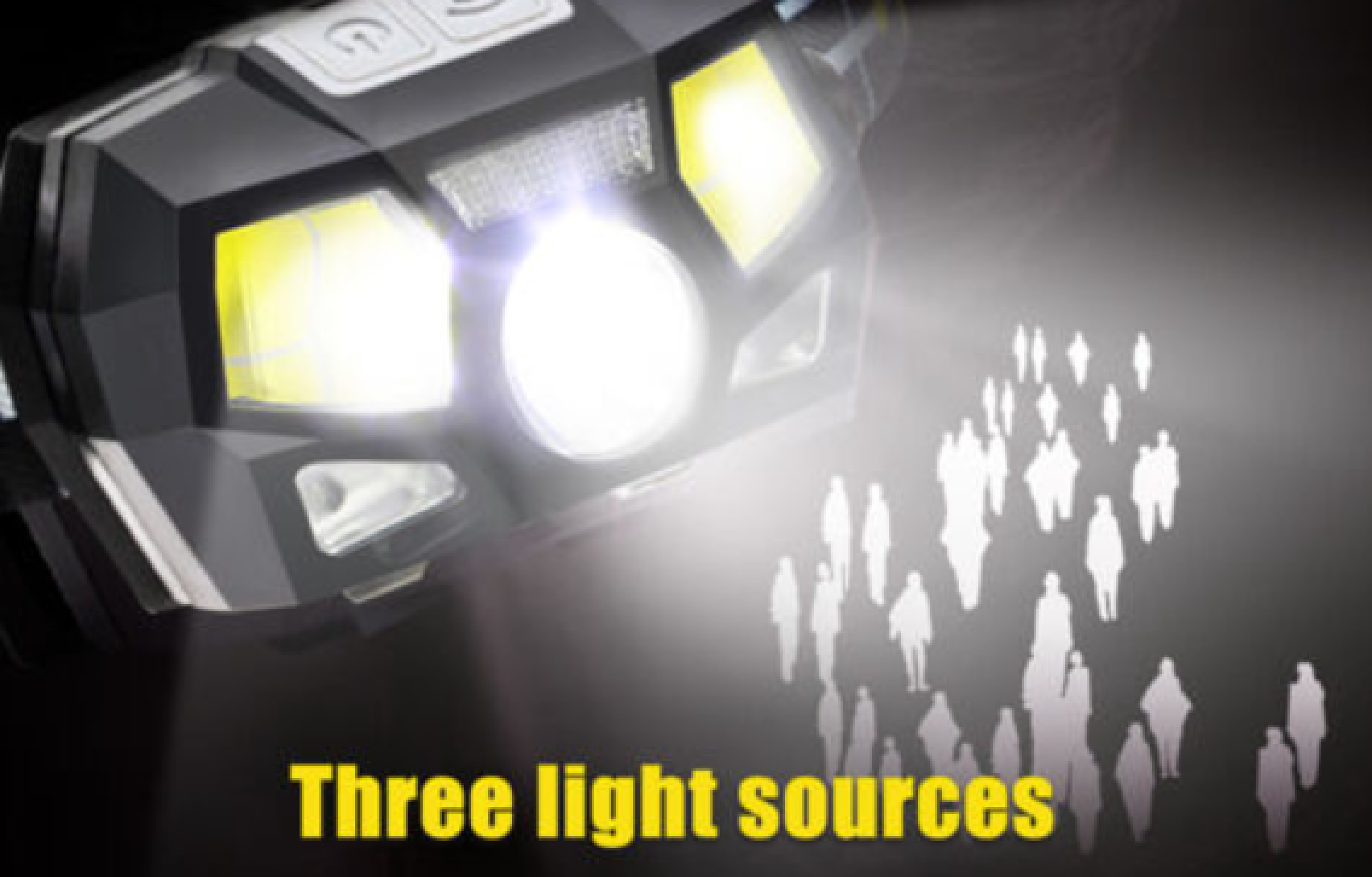 Ein schwarzer Scheinwerfer mit drei Lichtquellen leuchtet auf eine Gruppe von schemenhaften Menschen.