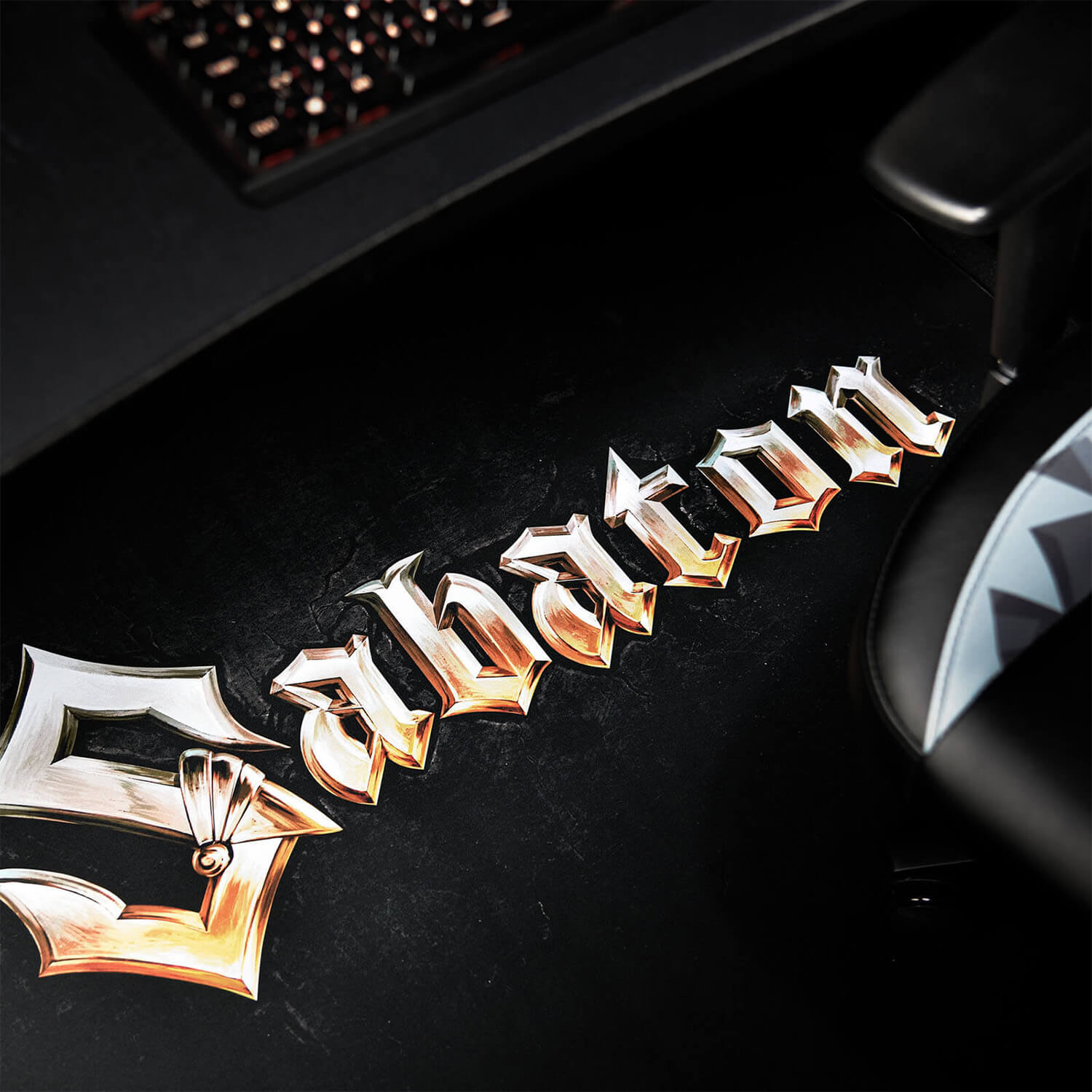 Ein silbernes und goldenes Logo mit der Aufschrift "Sabaton" auf schwarzem Untergrund.