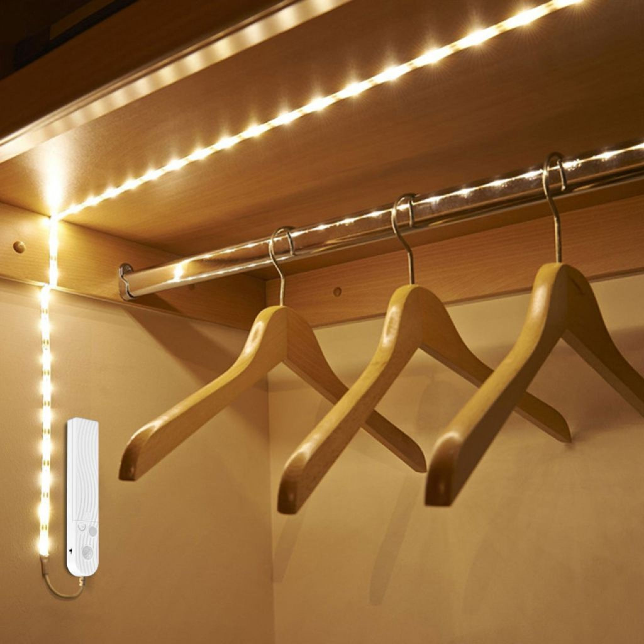 Ein Kleiderschrank mit LED-Lichtstreifen und Holzbügeln.