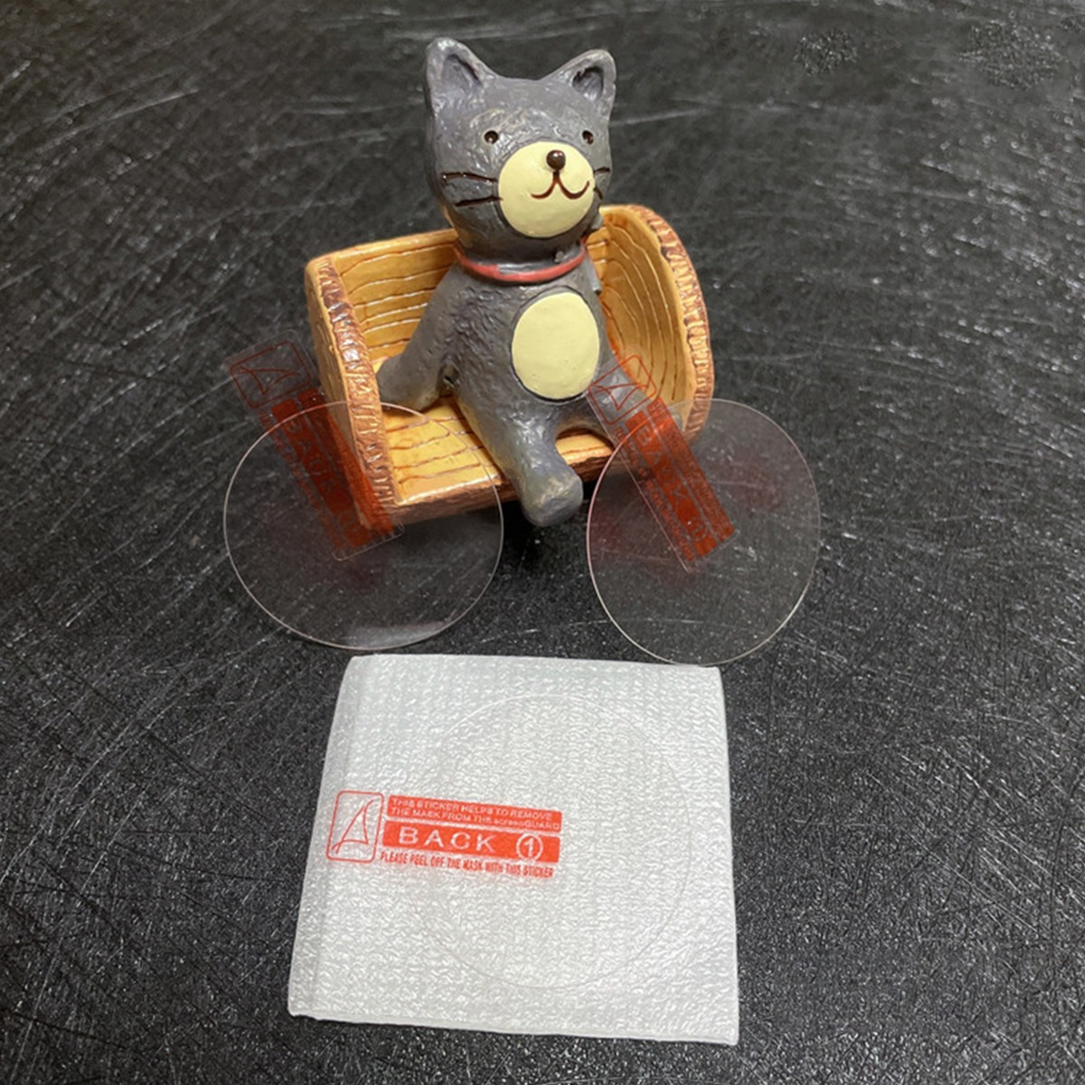 Una scultura di gatto seduta in un piccolo carrello con due lenti rotonde.