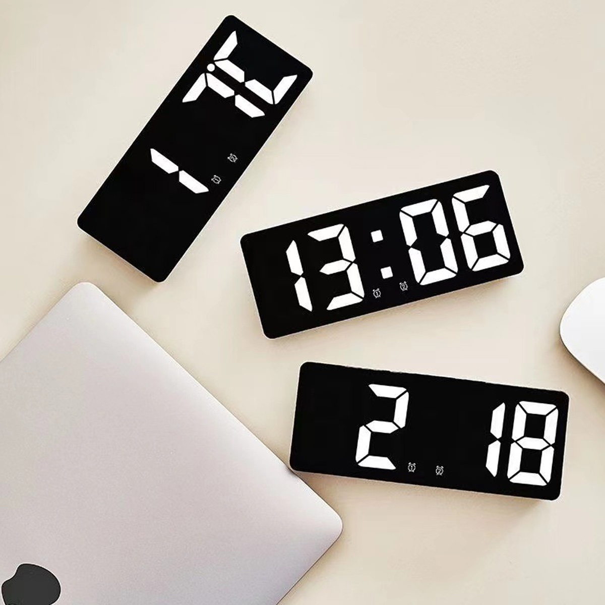 Drei Digitaluhren zeigen 1:24, 13:06 und 2:18. Ein Laptop ist in der Nähe.