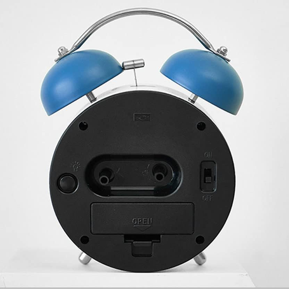 Rückseite eines blauen Doppelglockenweckers mit Schaltern und Batteriefach.