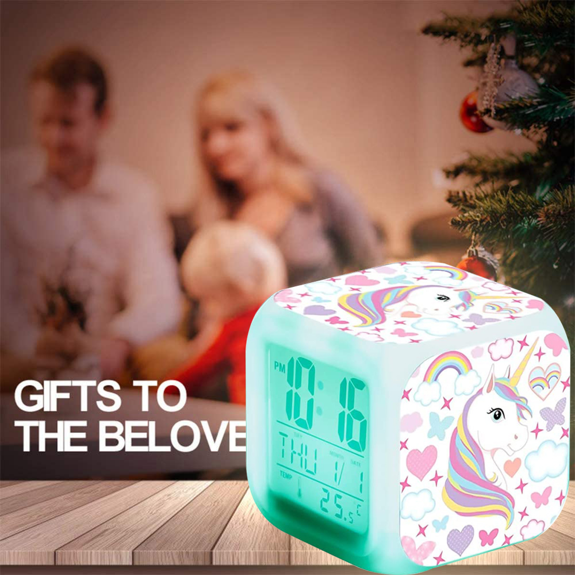 Ein digitaler Wecker mit Einhorn-Motiv auf einem Holztisch mit Familie im Hintergrund.