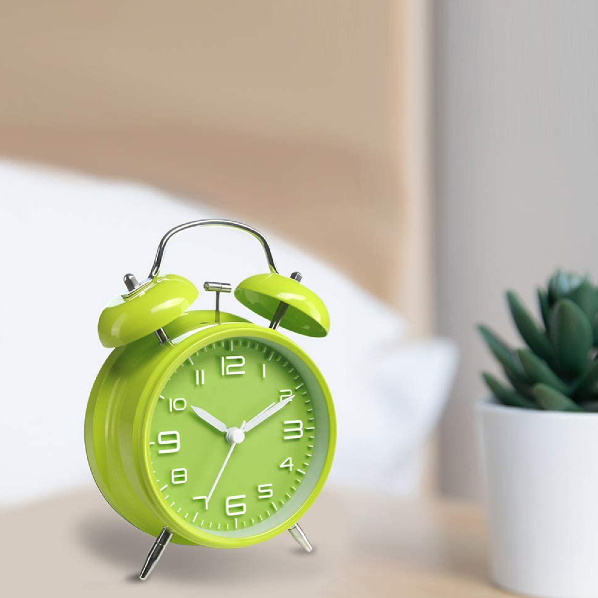 Eine leuchtend grüne Weckeruhr mit zwei Glocken und weißen Zahlen auf einem Tisch.