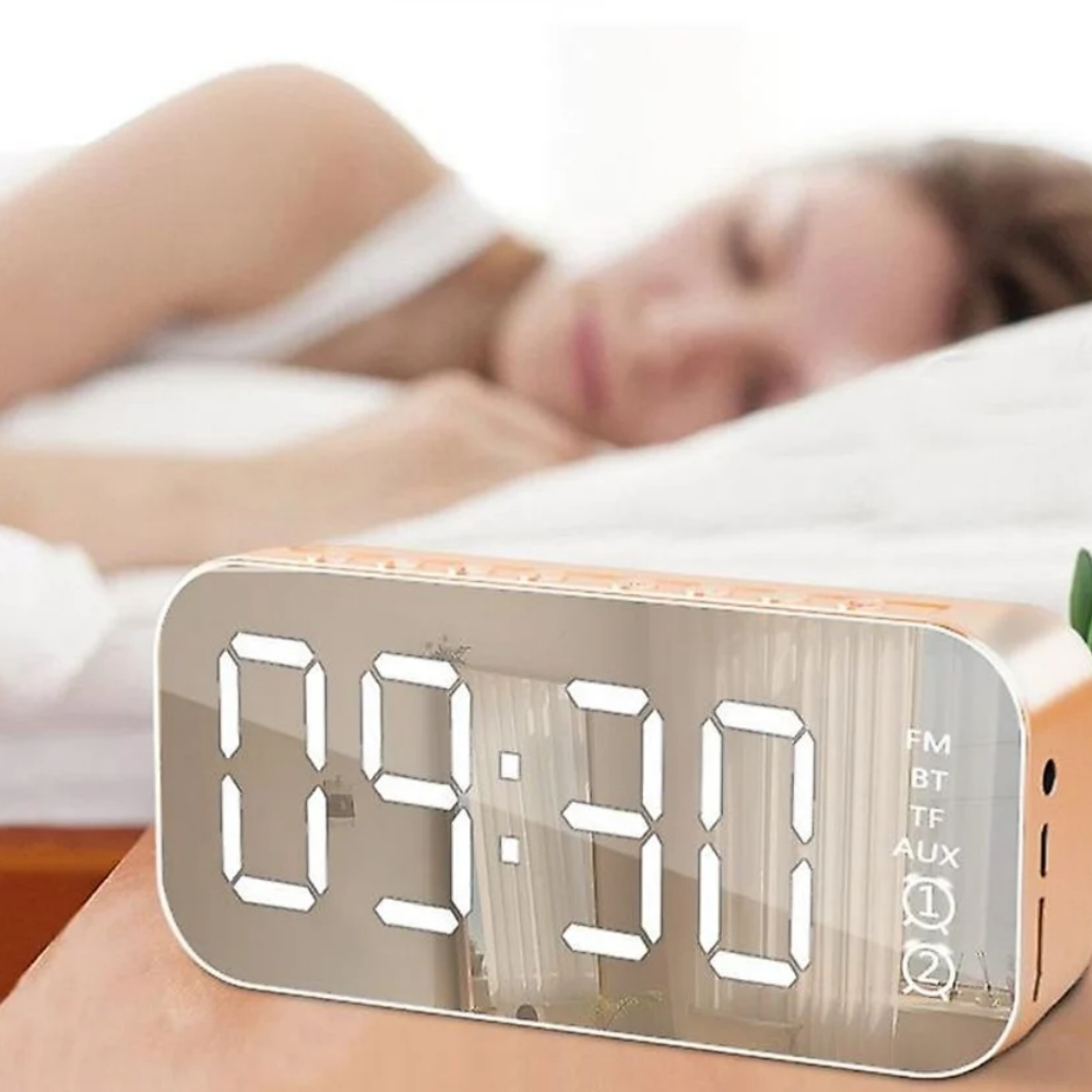 Ein digitaler Wecker zeigt 09:30 an, mit einer verschwommenen Person, die im Hintergrund schläft.