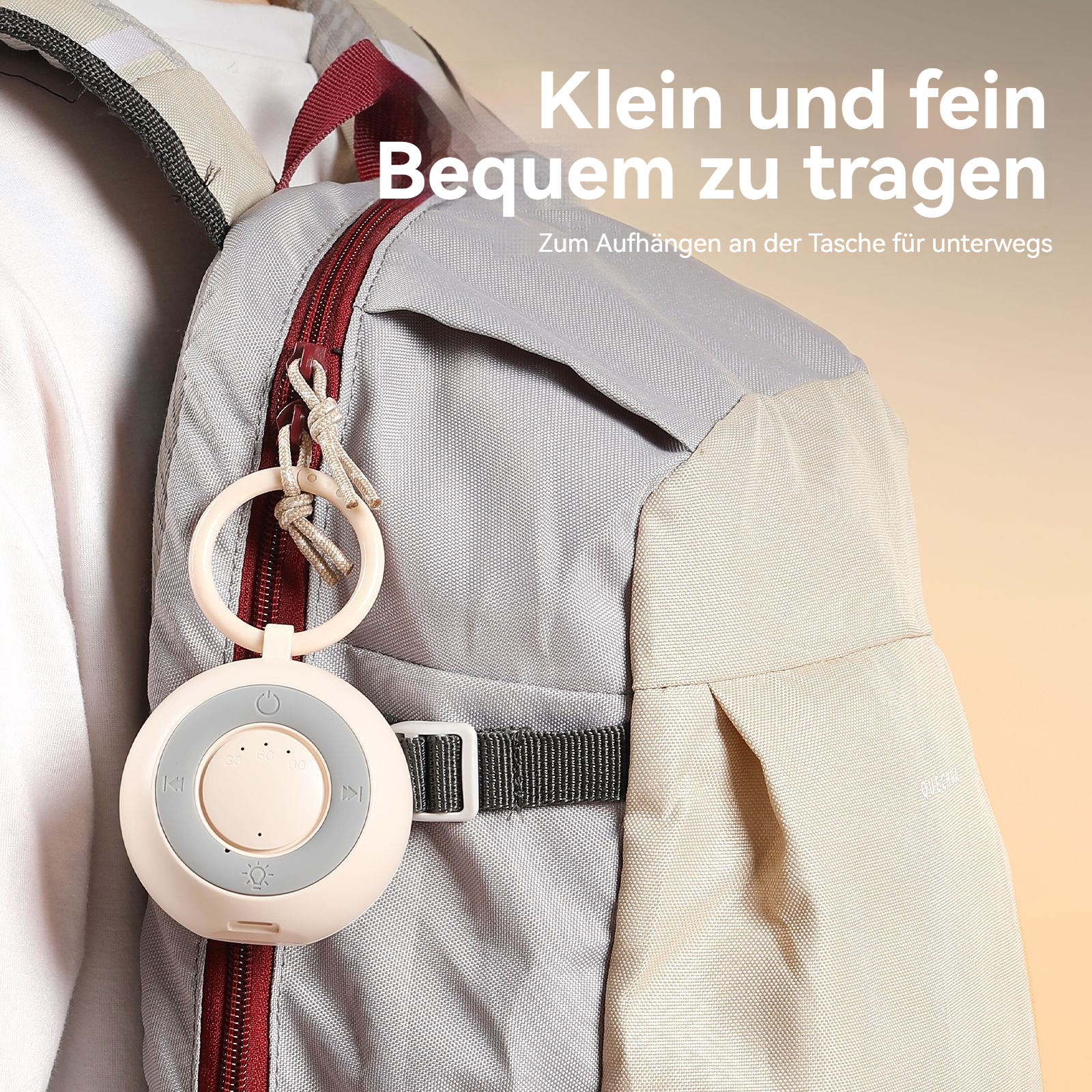 Ein kleiner, runder Lautsprecher mit Schlaufe hängt an einem Rucksack.