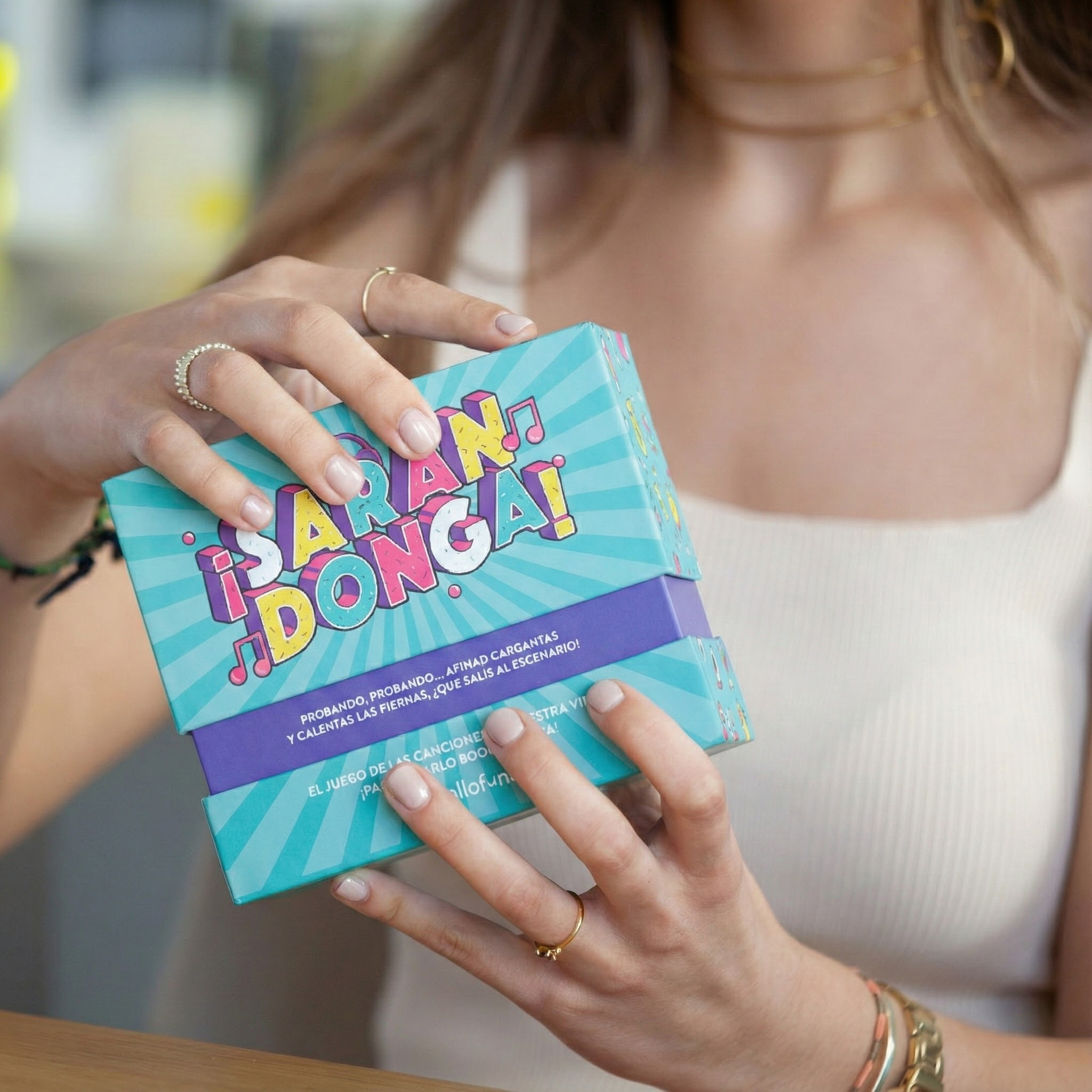 Una persona sostiene una colorida caja de juego con la etiqueta „¡SARAN DONGA!“.