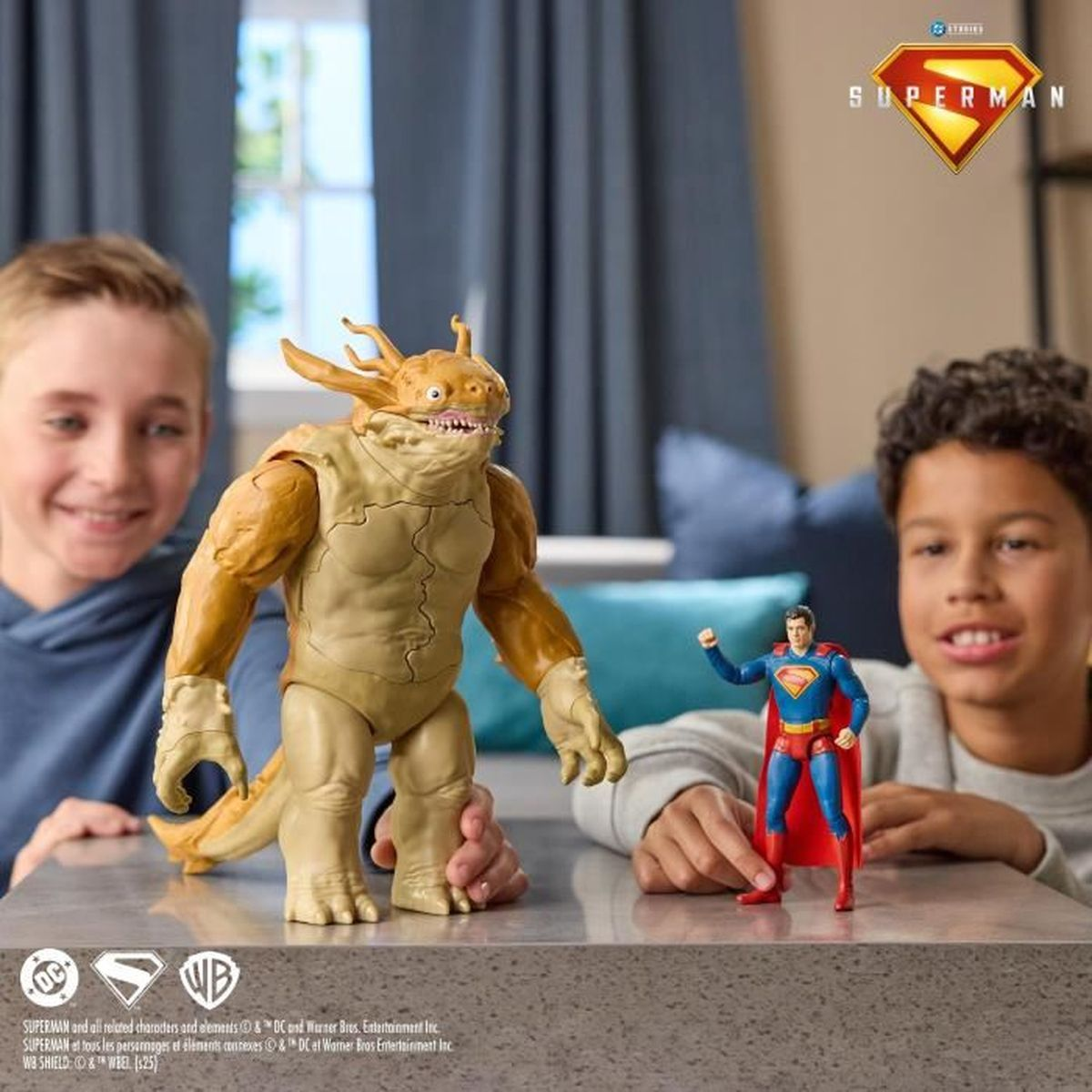 Dos niños juegan con figuras de acción de Superman y un monstruo.