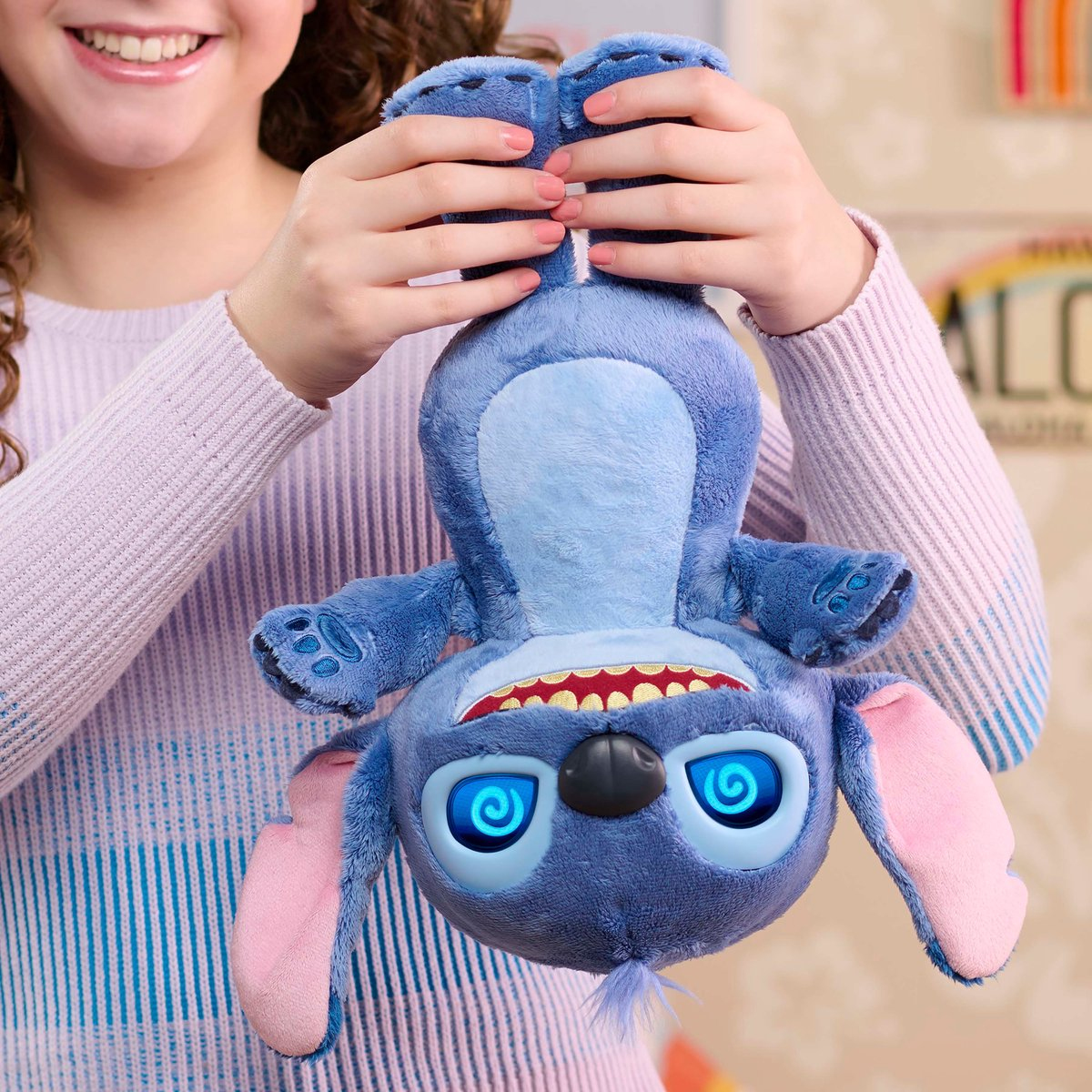 Un peluche blu di Stitch con occhi luminosi, tenuto da una persona con maglione viola.