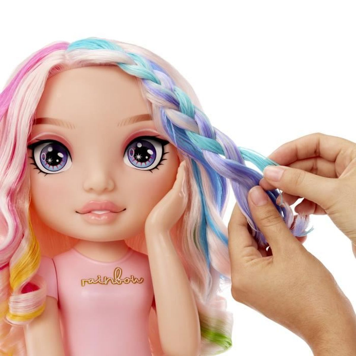 Puppe mit regenbogenfarbenem Haar, das von Händen geflochten wird. Rosa Hemd mit Aufschrift 'rainbow'.