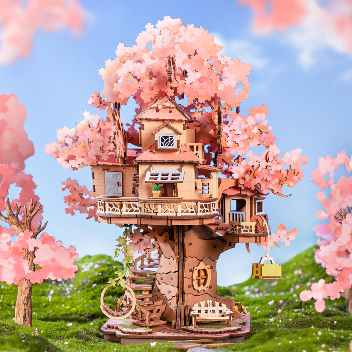 Ein detailliertes Holzmodell eines mehrstöckigen Baumhauses mit rosa Blüten vor blauem Himmel.