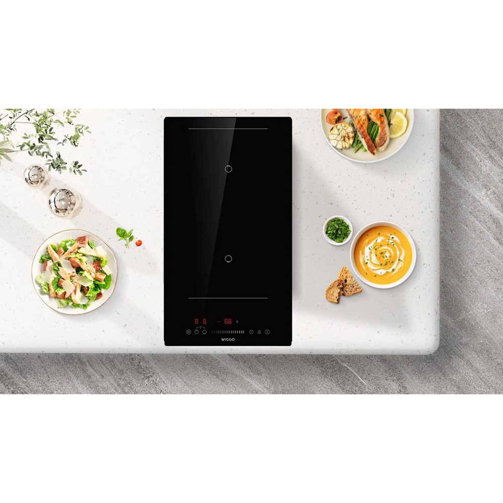 Zwart inductiefornuis met twee kookzones, ernaast salade, soep en vis.
