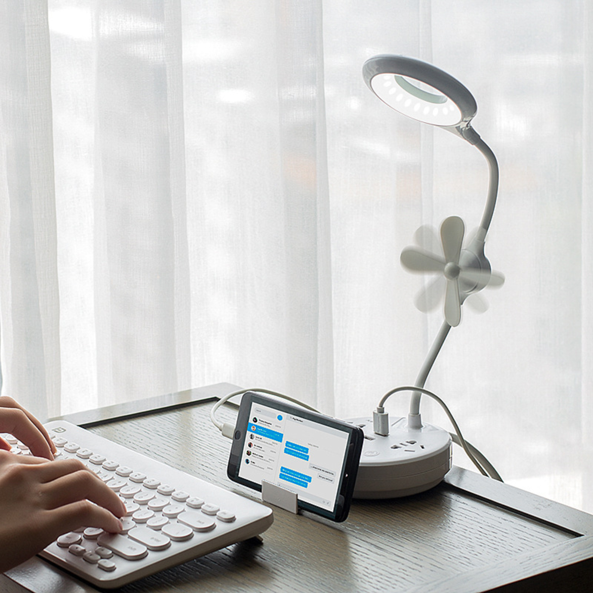 Ein Schreibtisch mit Tastatur, Tablet und einer Multifunktionslampe mit Ventilator.