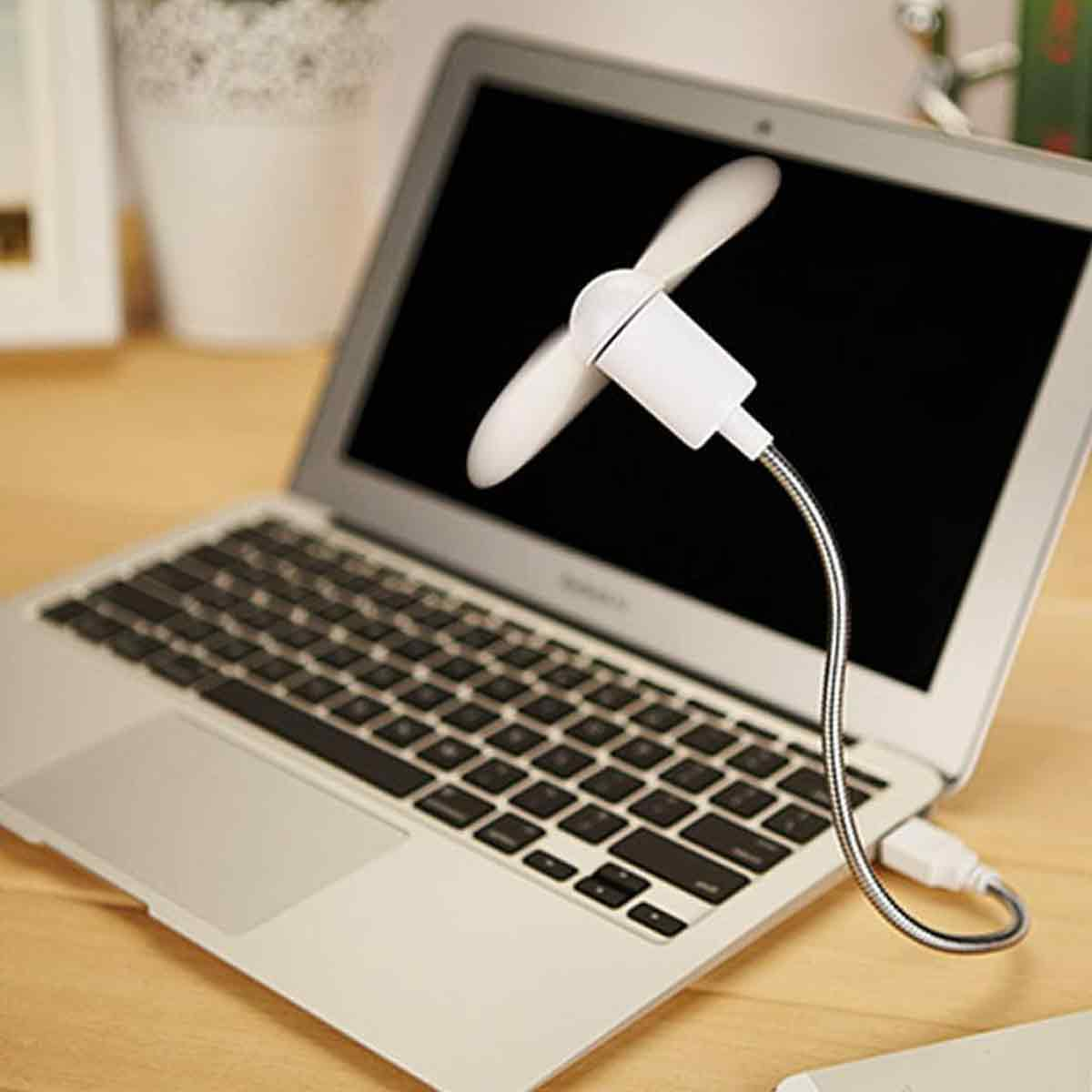 Ein kleiner weißer USB-Ventilator ist an einen geöffneten Laptop angeschlossen.